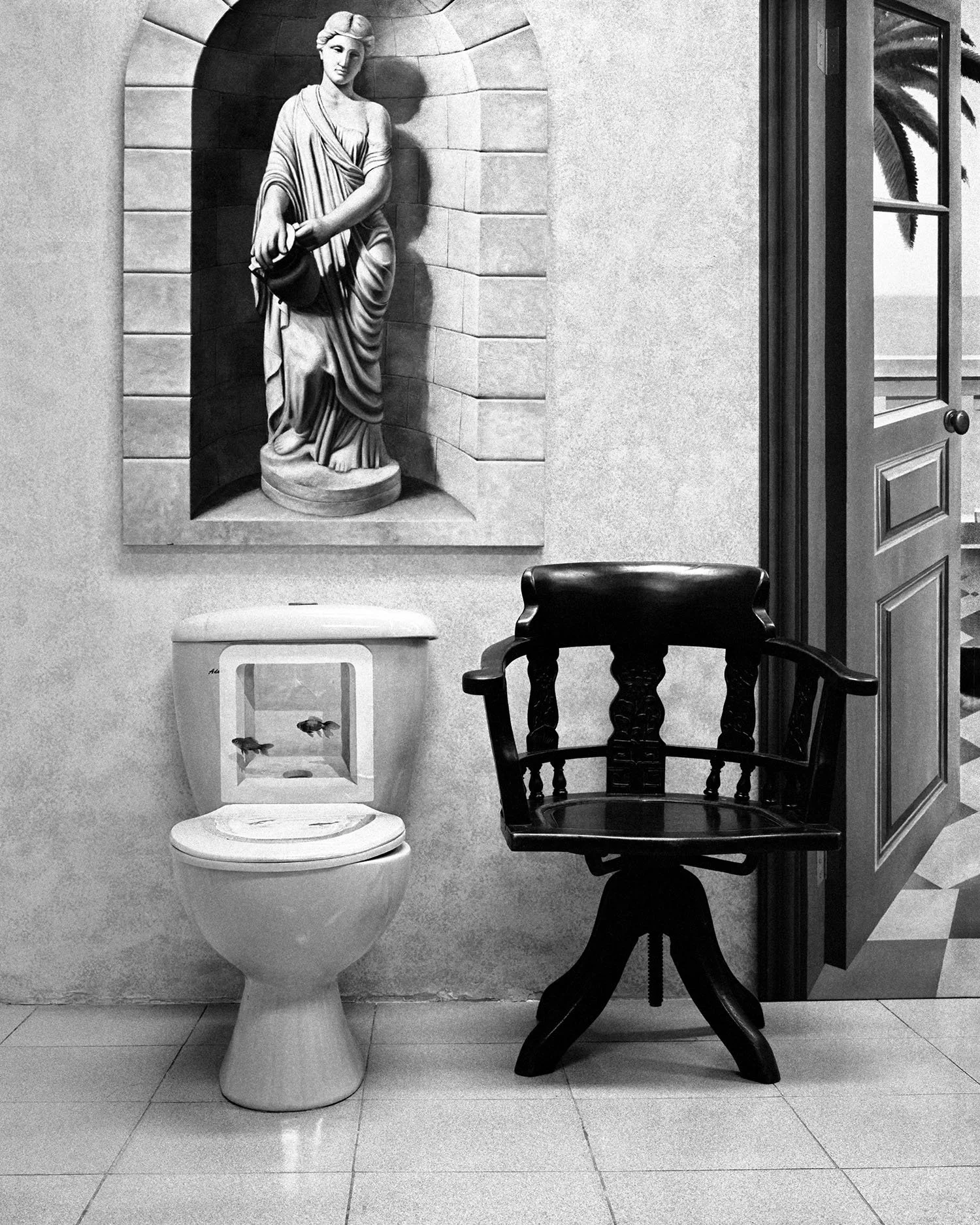 Toilet with a painted fishbowl and a wooden chair situated within a muralist's studio in Shanghai, 2003, positioned behind a painted wall mural depicting a statue and an open doorway.