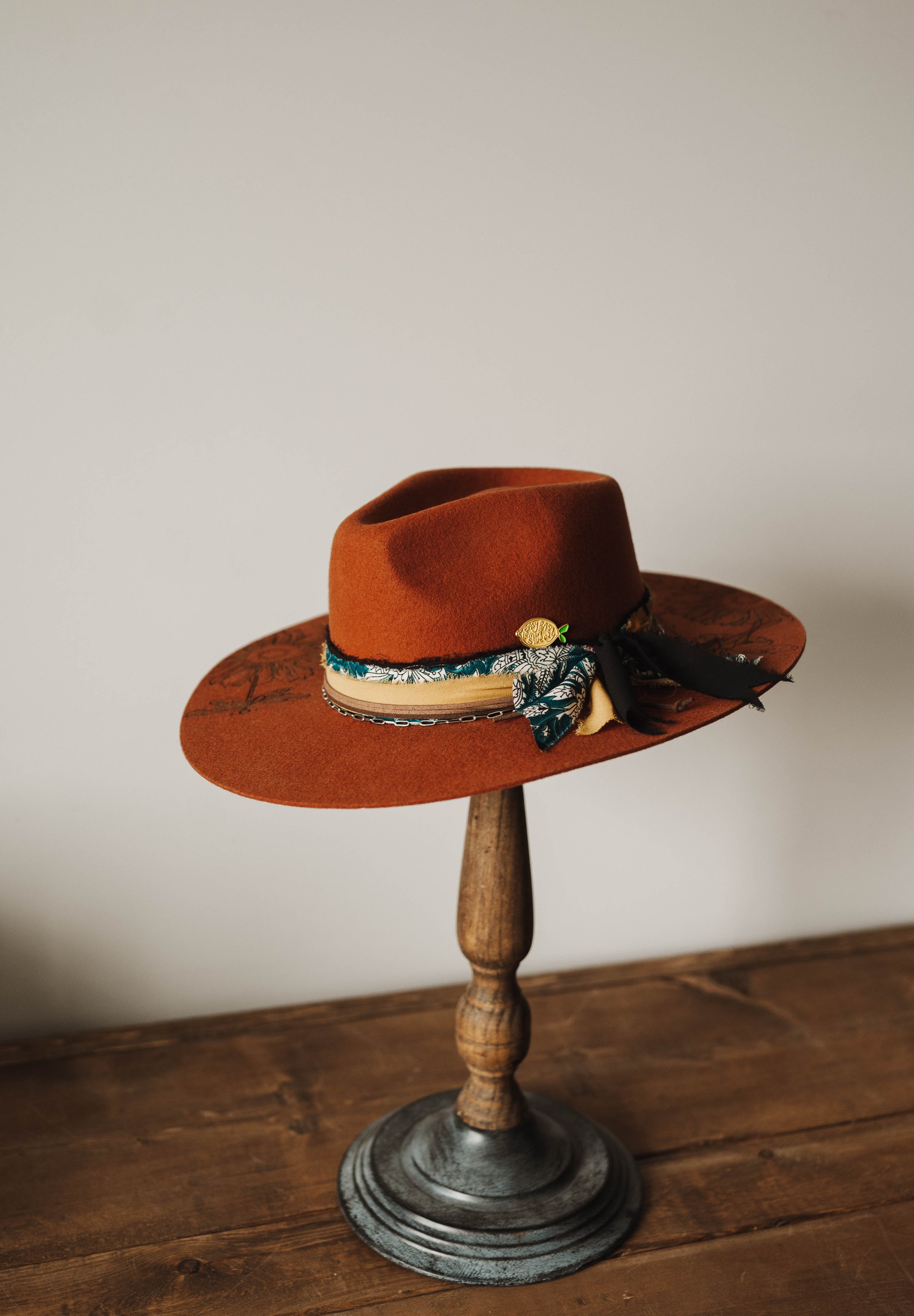Brown felt hat with decorative band on wooden stand
