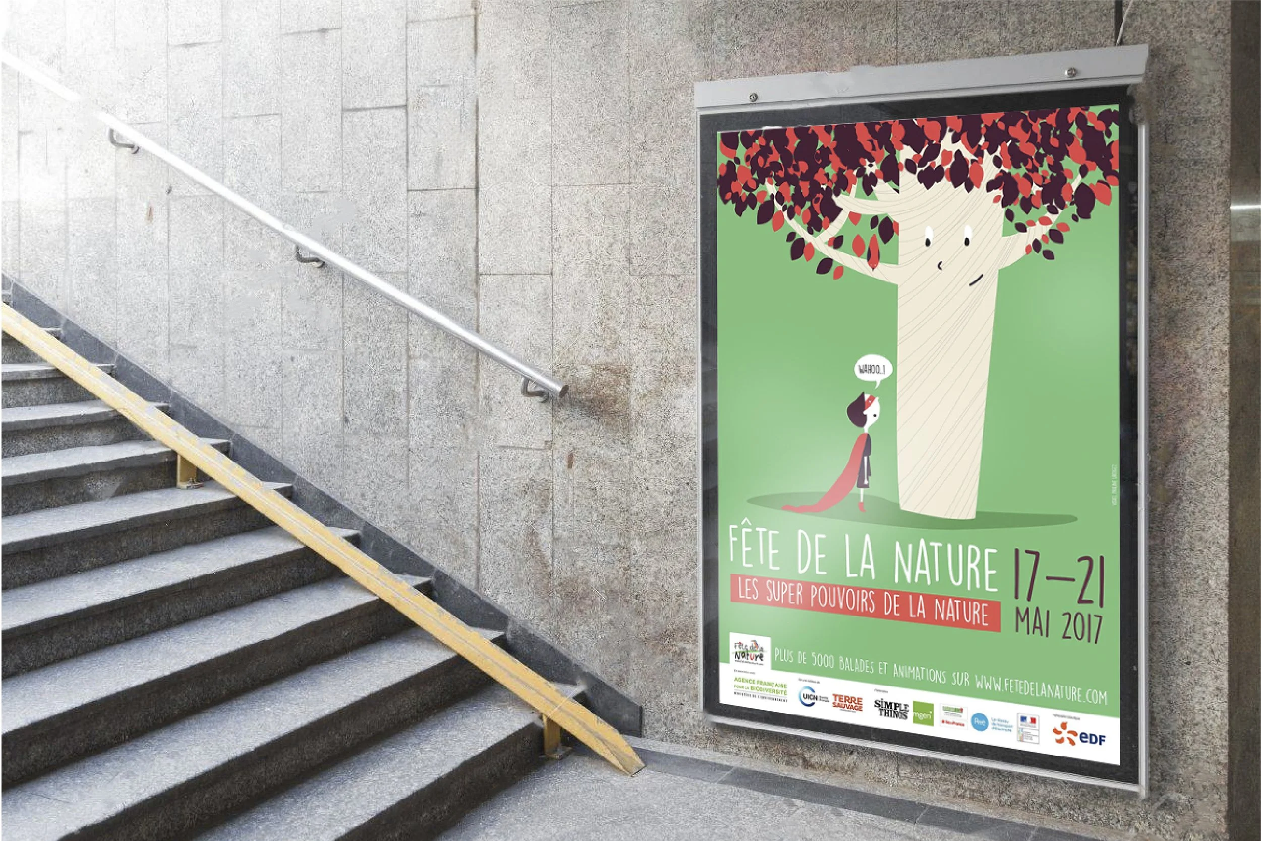 Une affiche promotionnelle pour la Fête de la Nature 2017 à proximité d'un escalier en pierre. L'illustration représente un arbre avec un visage enfantin et un large sourire, ses branches remplie de feuilles rouges, vertes et violettes. Le texte indique la date de l'événement, du 17 au 21 mai 2017, et encourage la participation à plus de 5000 activités en plein air.