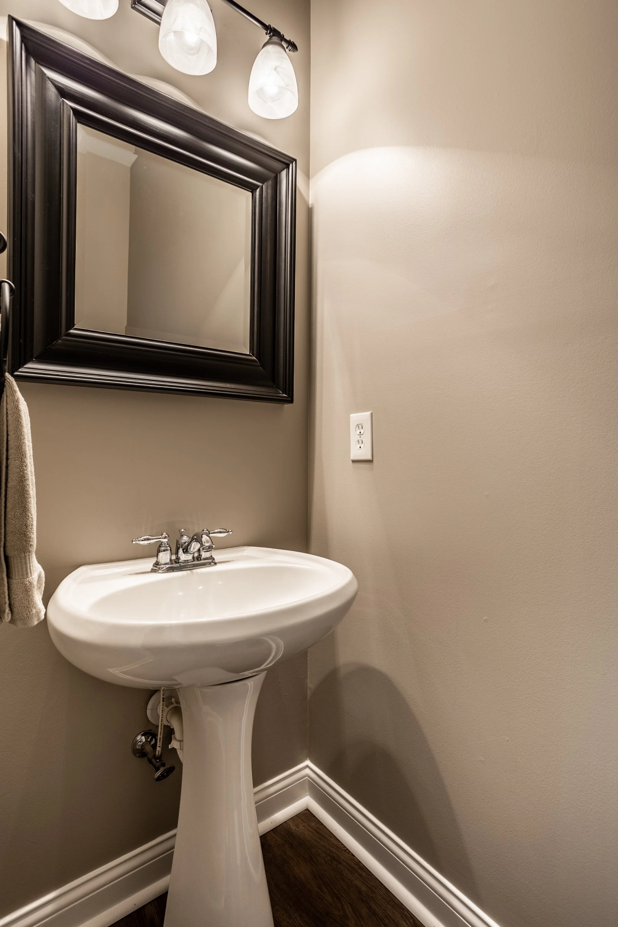 Small bathroom with a pedestal sink, wall-mounted mirror, and overhead lighting.