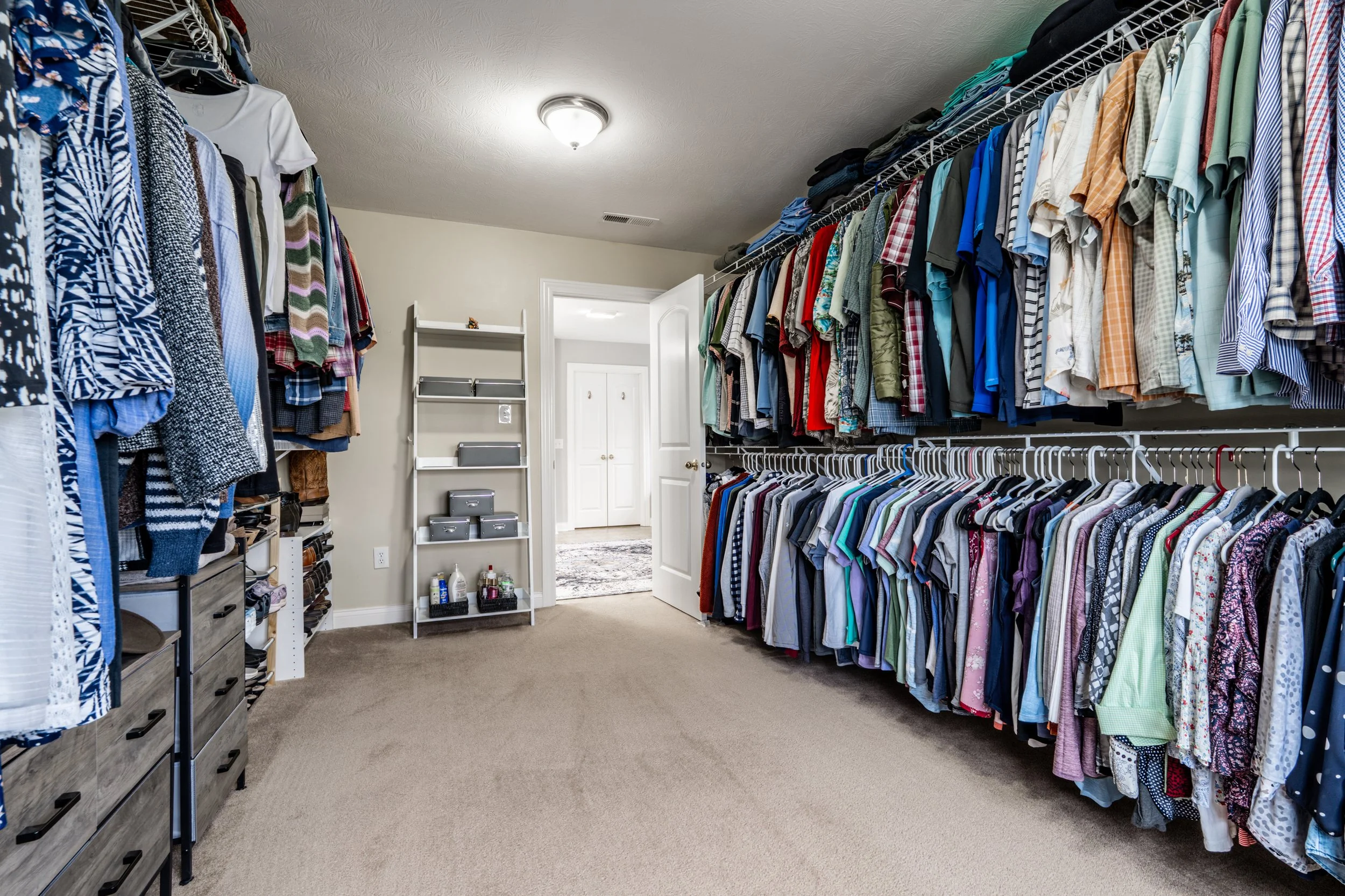 Walk-in closet with organized clothing on hangers and shelves.
