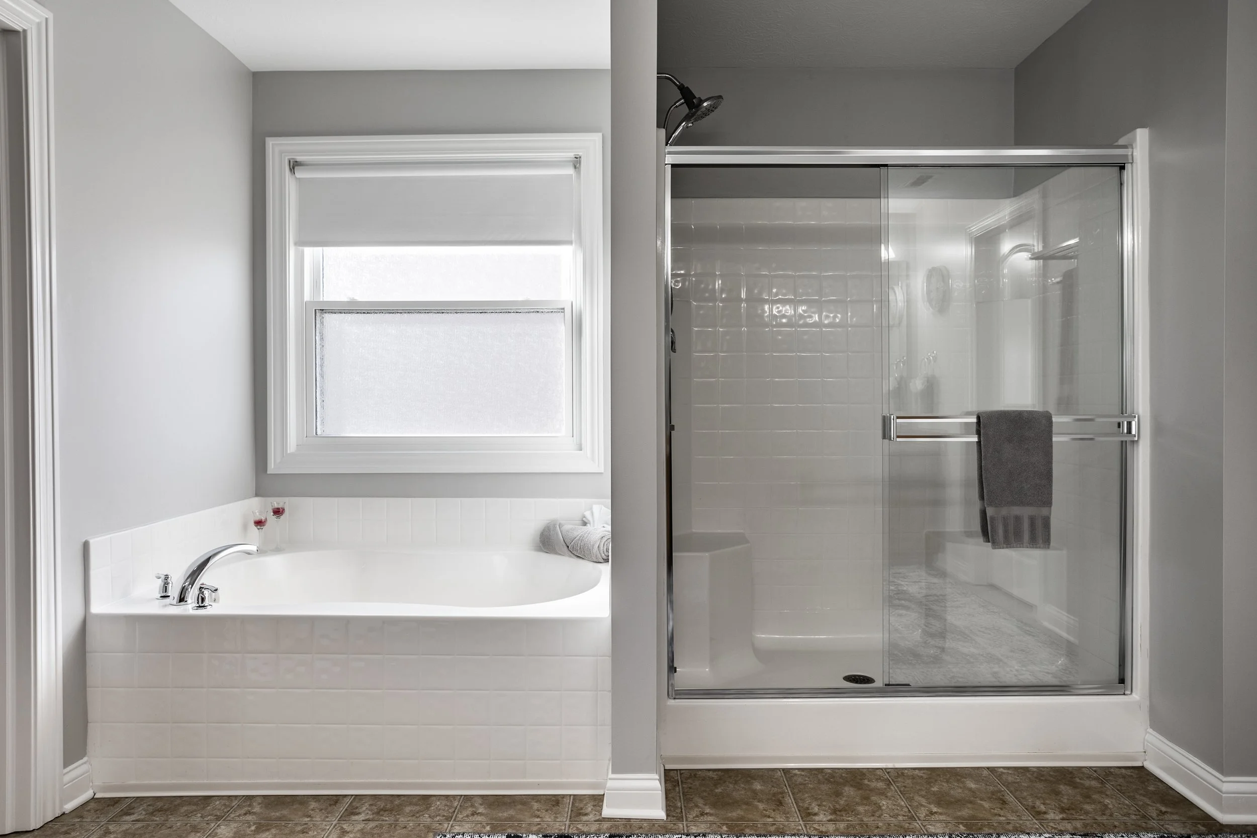 Modern bathroom with bathtub and glass-enclosed shower next to a window.