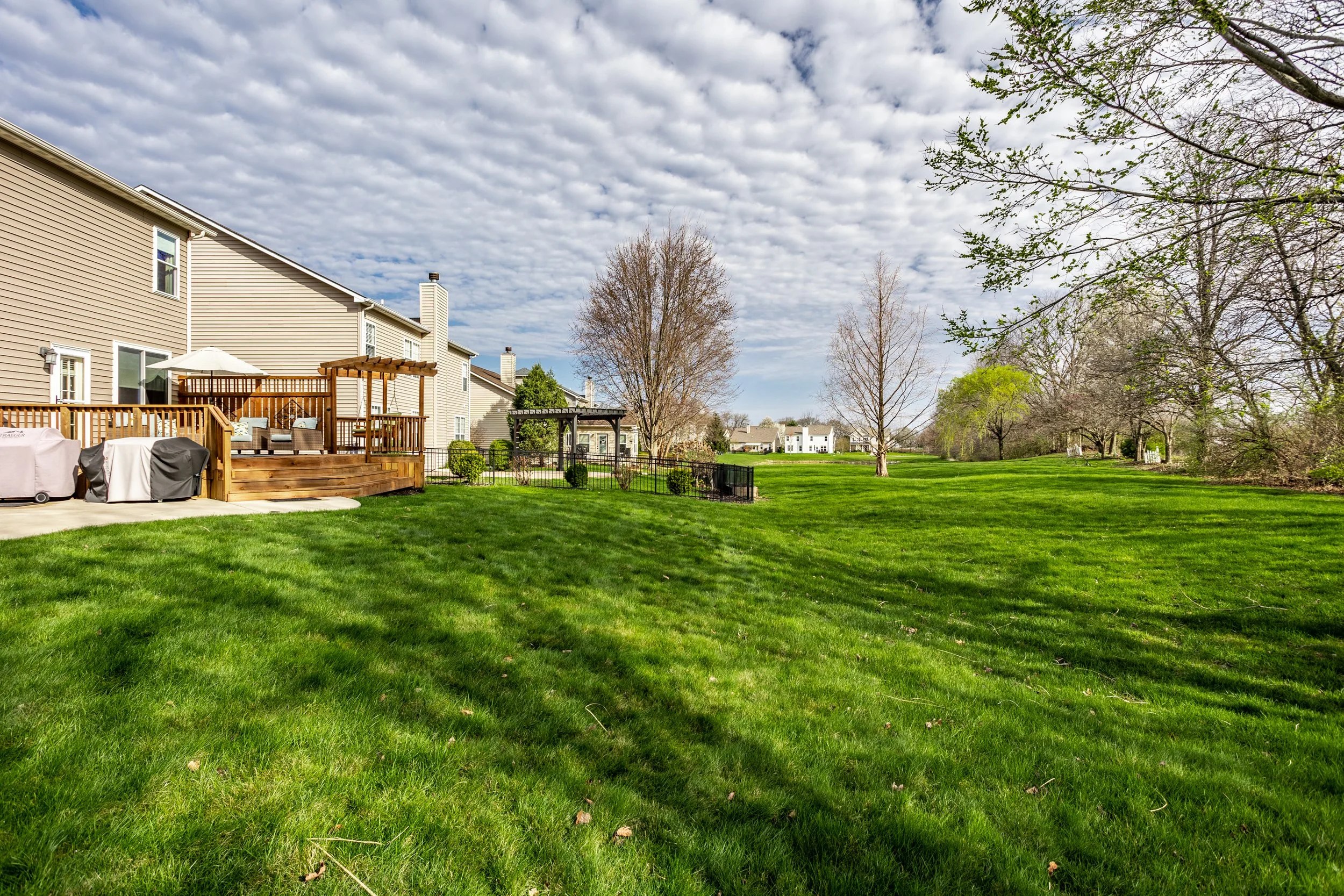 Backyard with a wooden deck, outdoor furniture, and green lawn