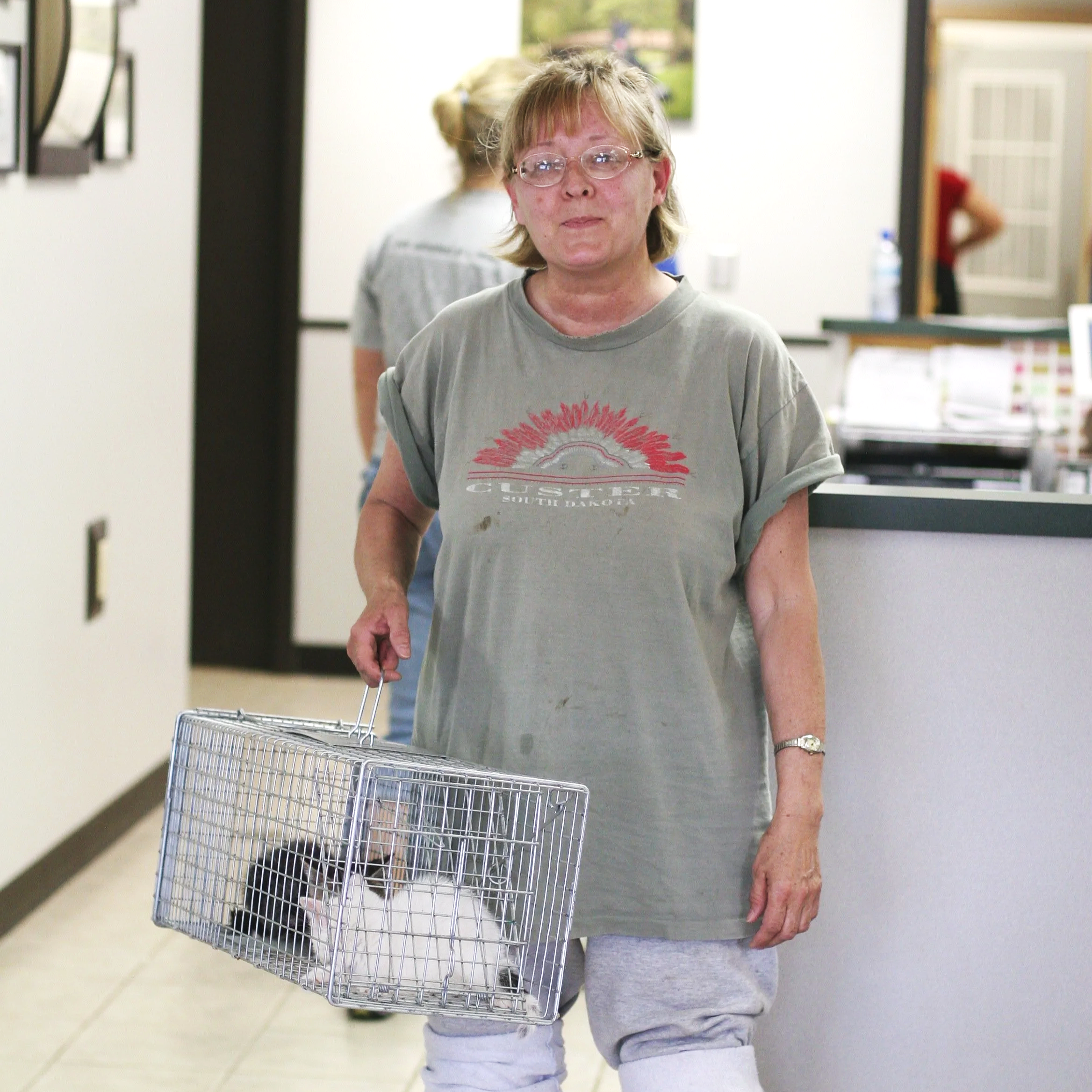 Camp Companion volunteer holds live trap with two kittens inside at vet office awaiting TNR