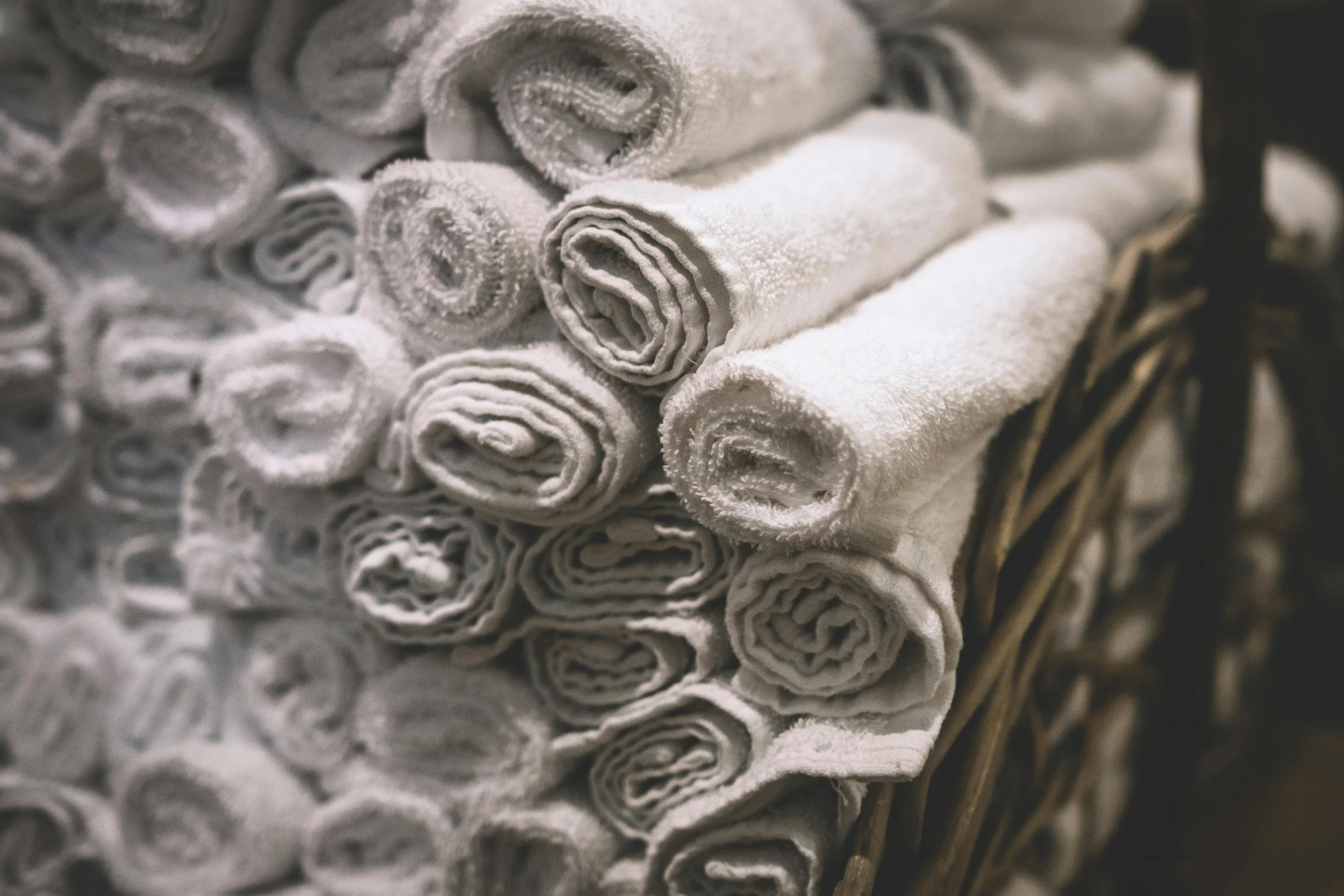 Close-up of a basket of neatly rolled white towels.