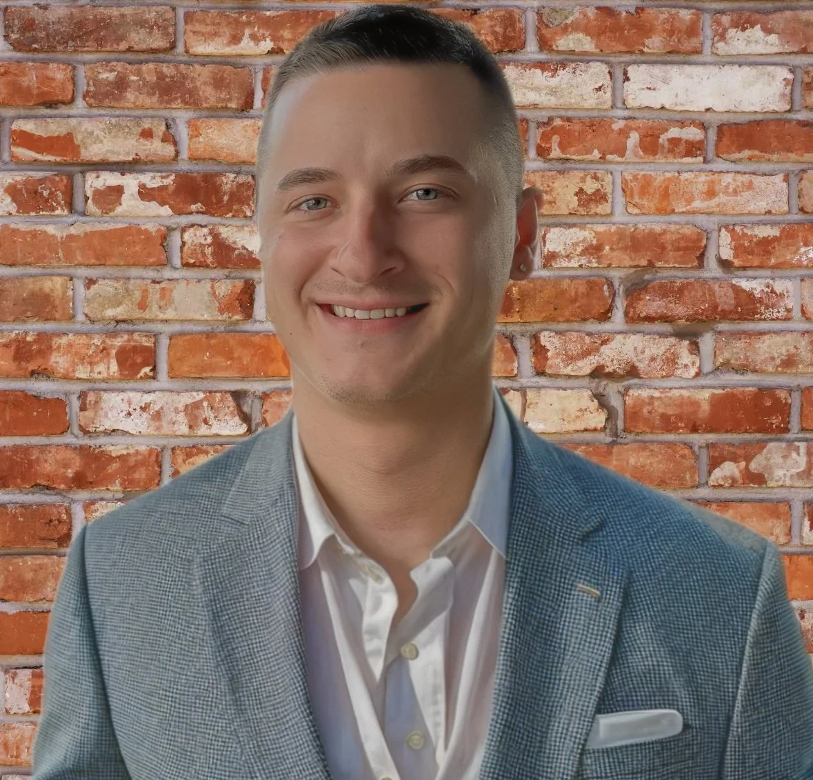 Man smiling indoors with a decorative shirt, background city view through a window.