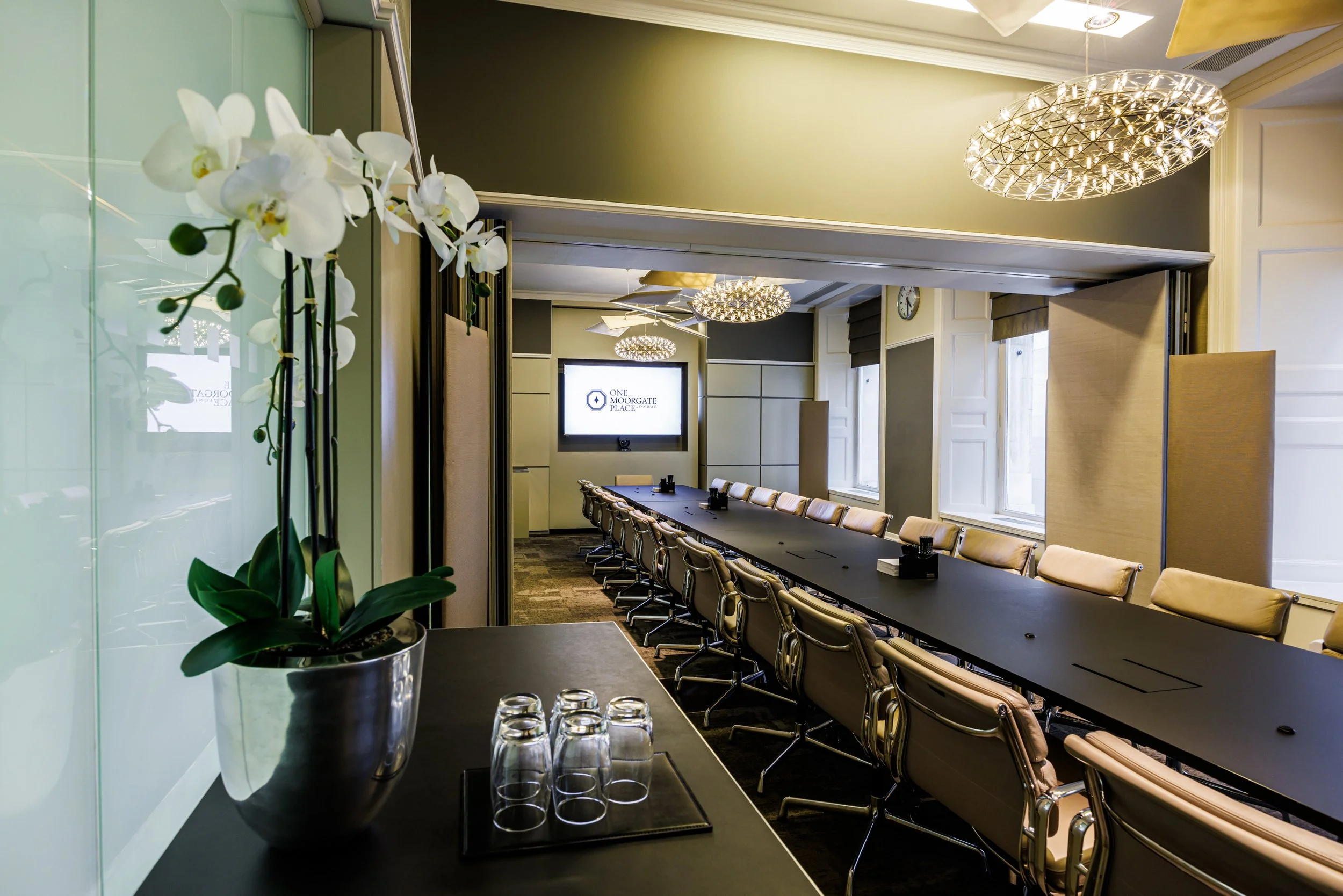 Contemporary conference room setup with long table and decorative chandelier