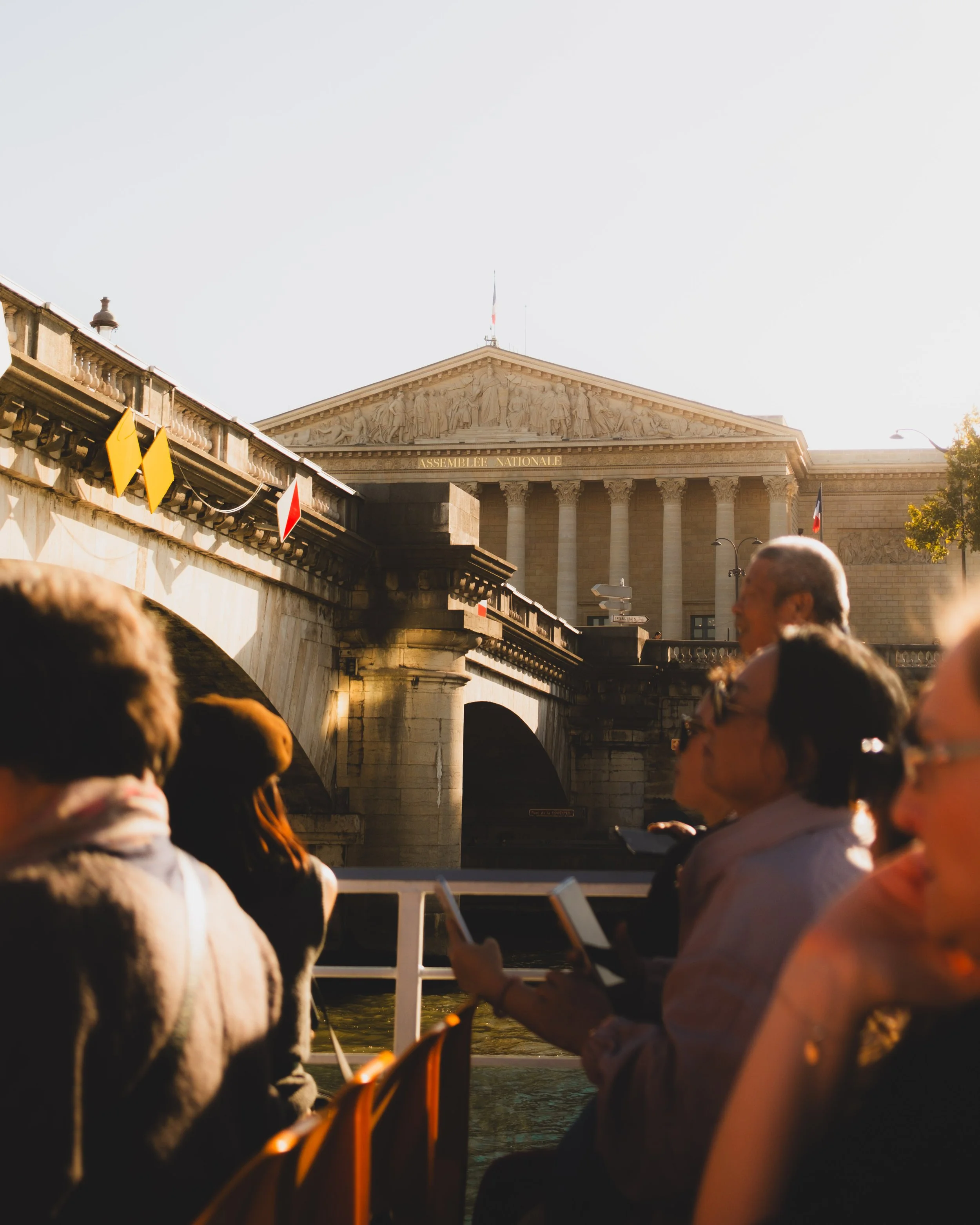 People on a boat tour along the Seine River in Paris with the Palais Bourbon in the background. Lionel Chu - Hotel & Travel Photographer