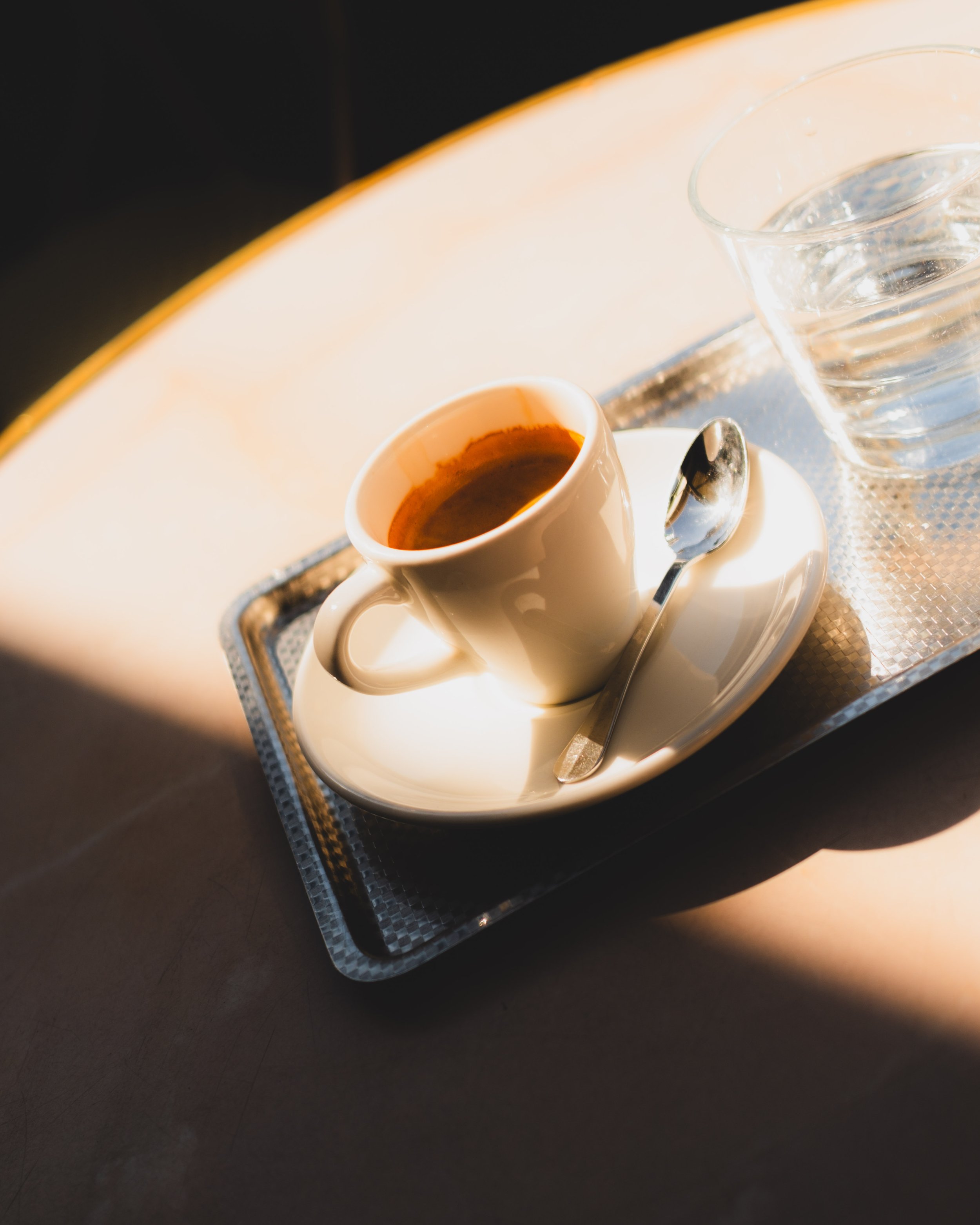 Espresso cup on saucer with spoon on a metal tray. Lionel Chu - Hotel & Travel Photographer.