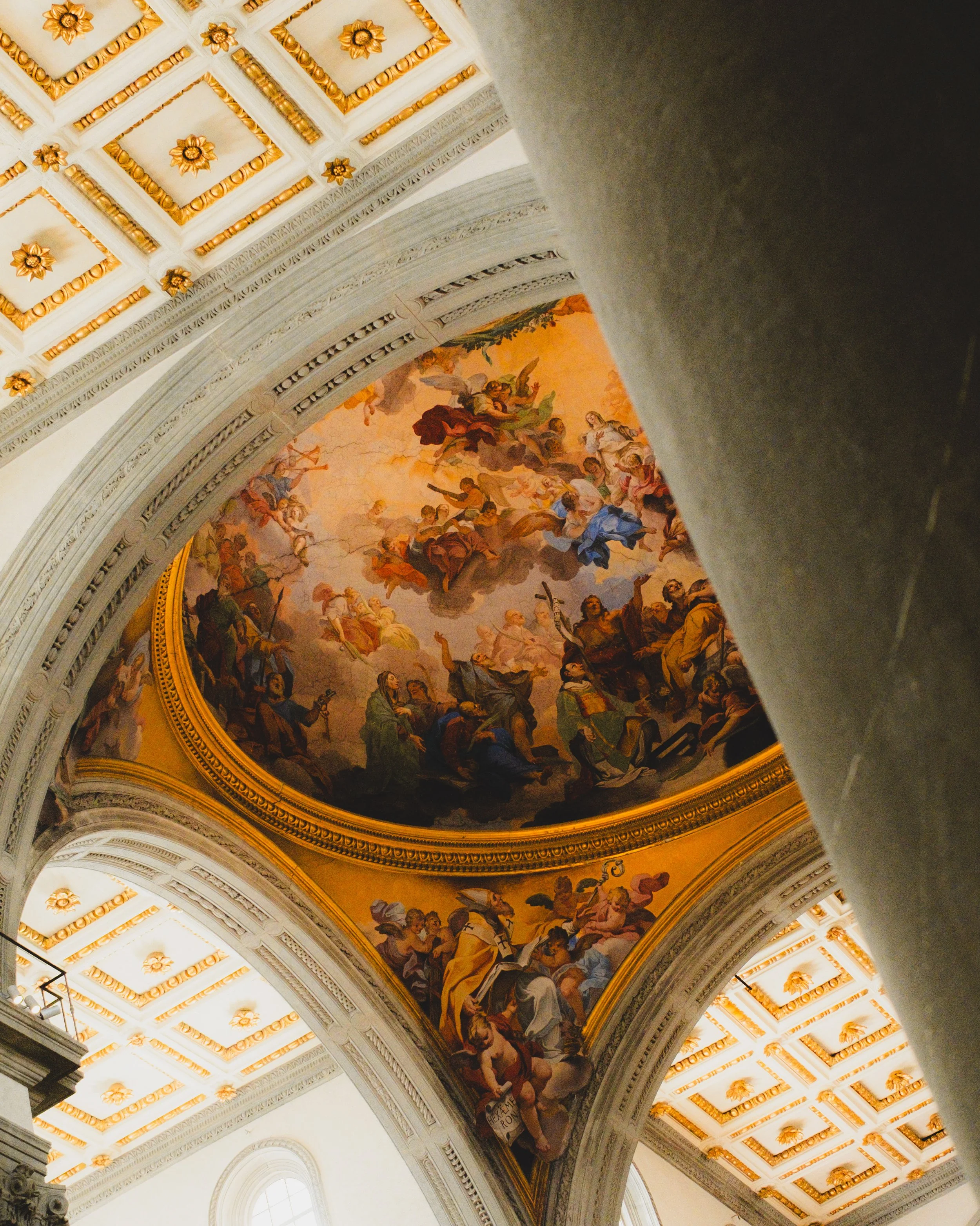Ceiling fresco in a church or cathedral depicting religious figures and angels, with ornate gold and white architectural details. Lionel Chu - Hotel & Travel Photographer