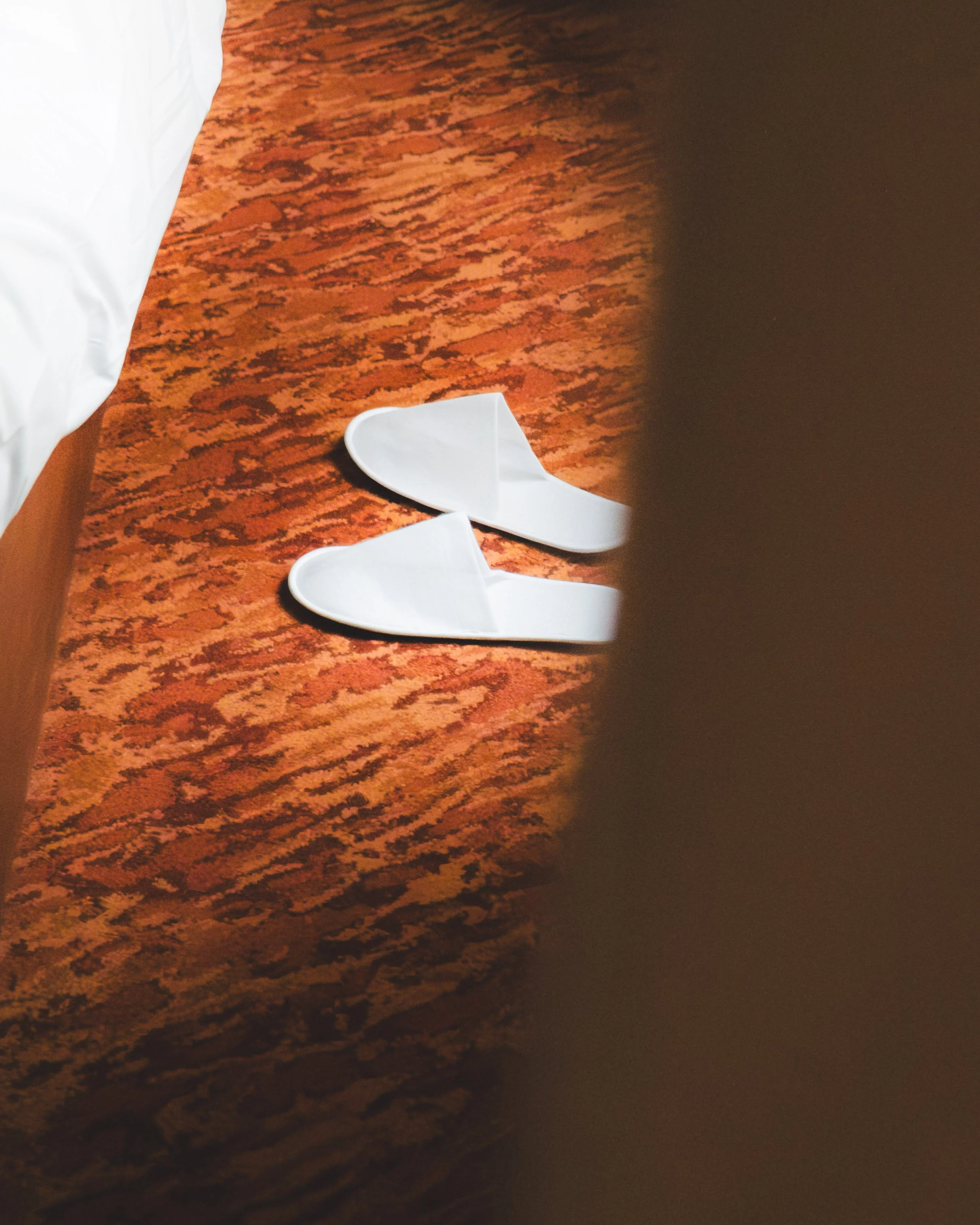 Close-up of a wooden surface with a white paper on top, partially visible, and two white folded paper objects on the surface.