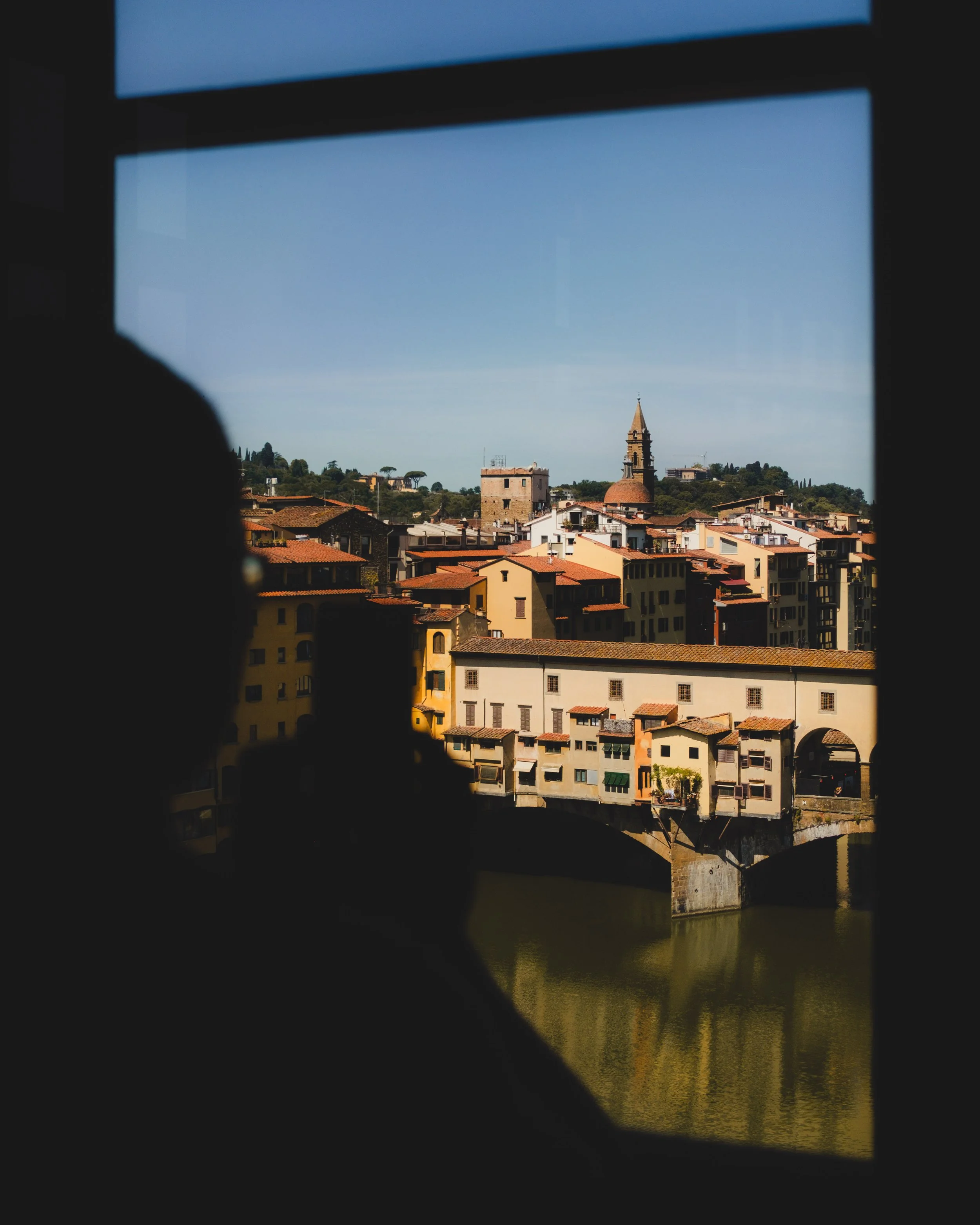 Cityscape viewed through a window, silhouette of a person taking a photo with a smartphone. Lionel Chu - Hotel & Travel Photographer