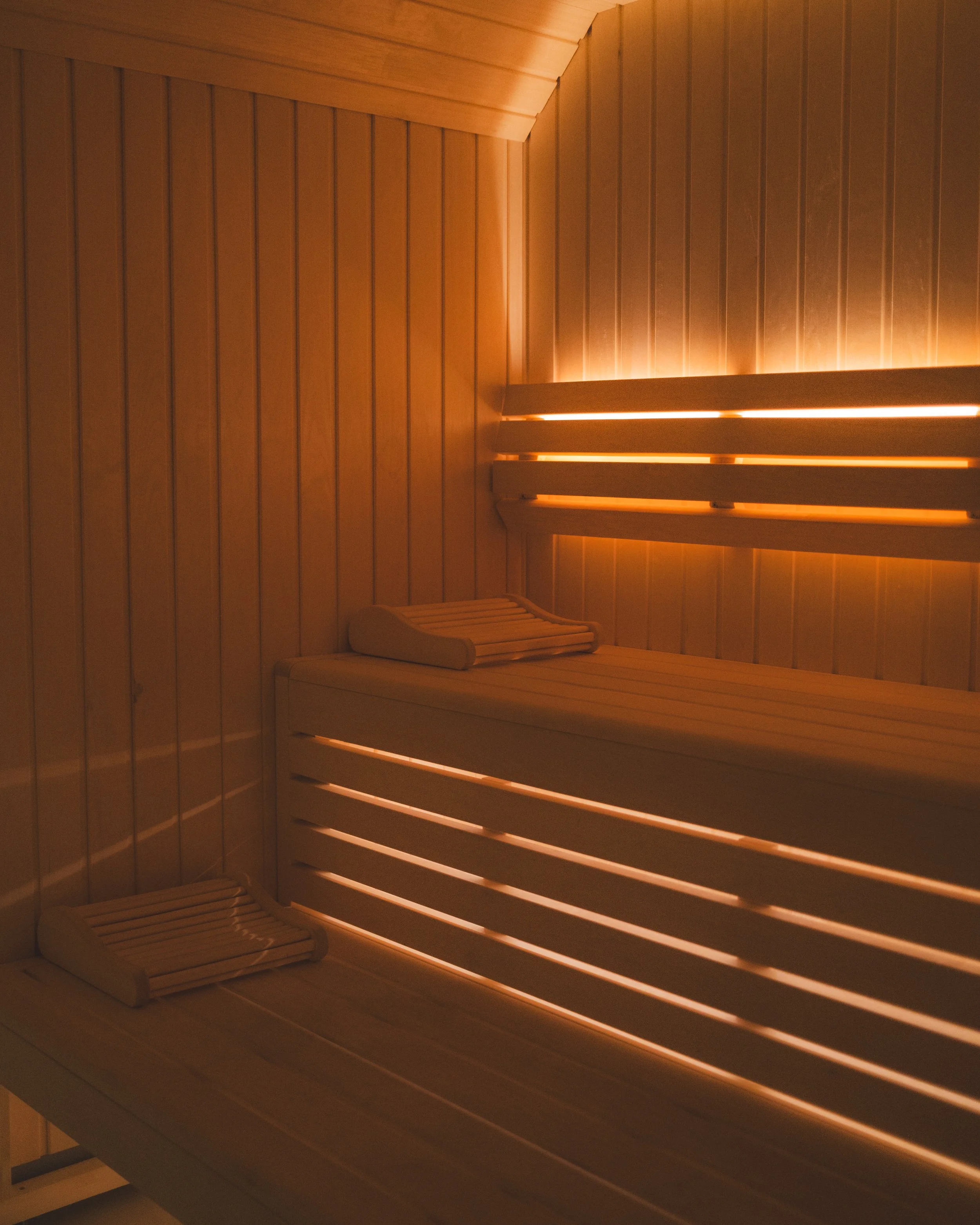 Interior view of a wooden sauna with benches and warm lighting.