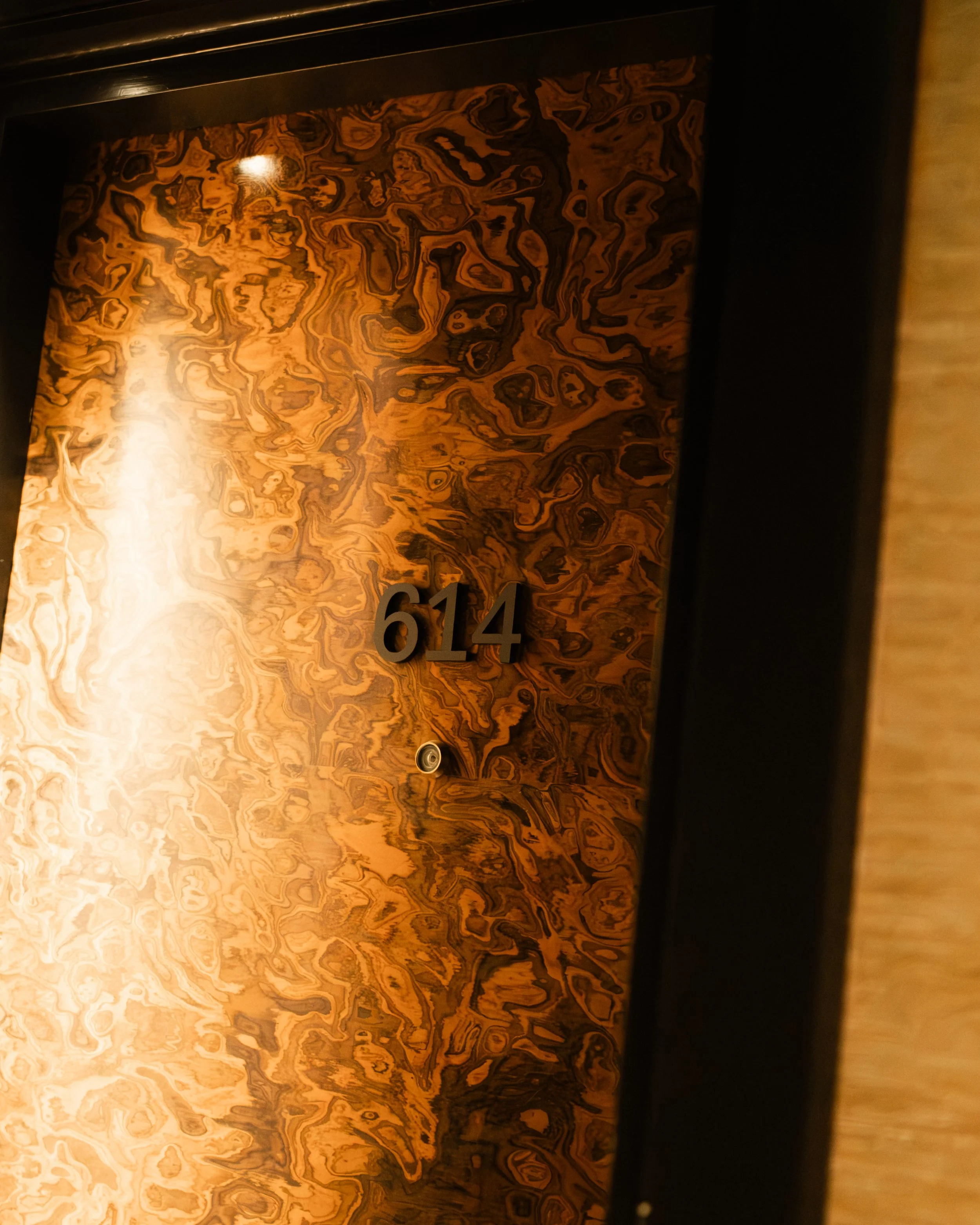 Hotel room door with wood grain finish, black door frame, and the number 614 displayed. Lionel Chu - Hotel & Travel Photographer