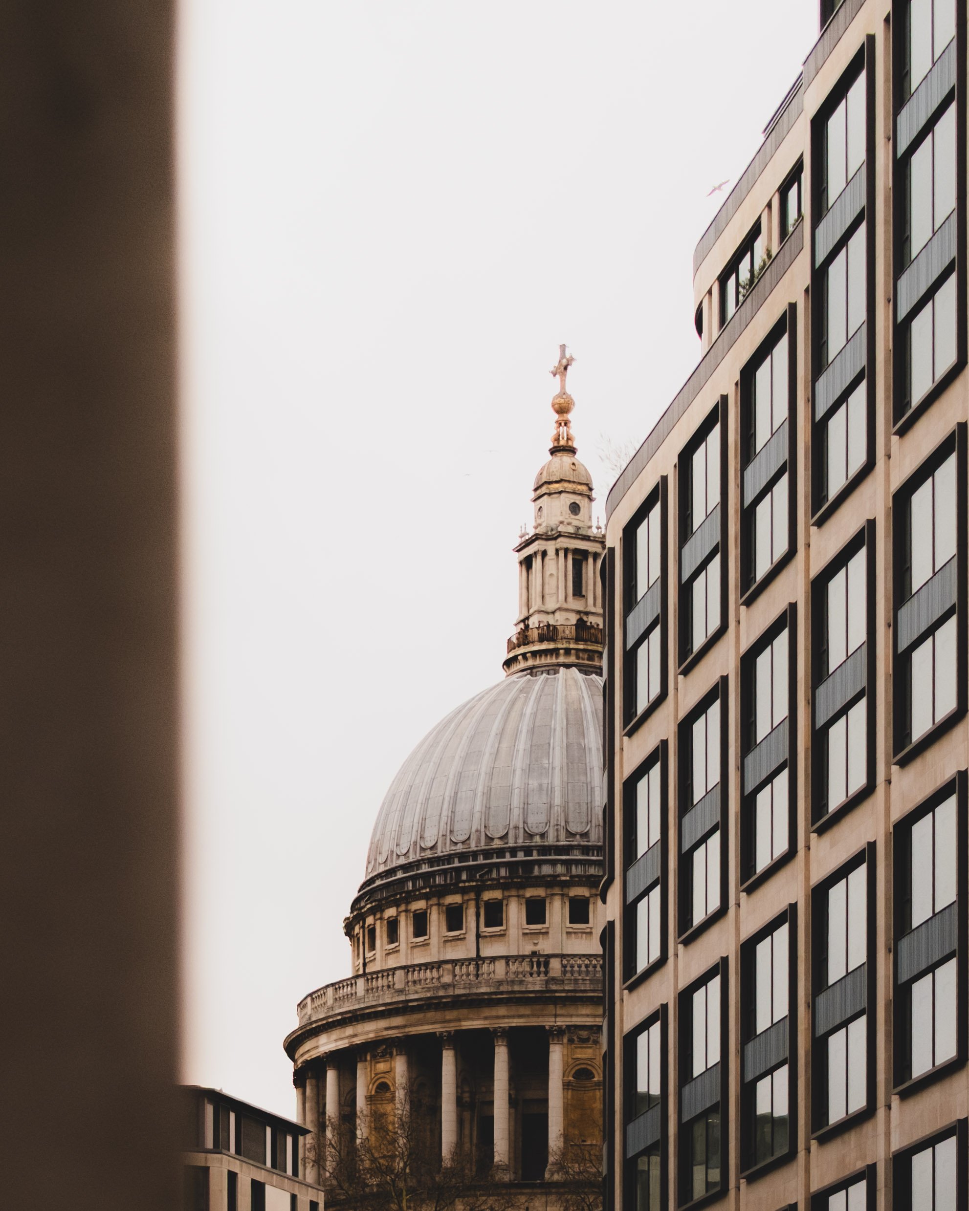 View of St. Paul's Cathedral dome framed between modern buildings in London. Lionel Chu - Hotel & Travel Photographer