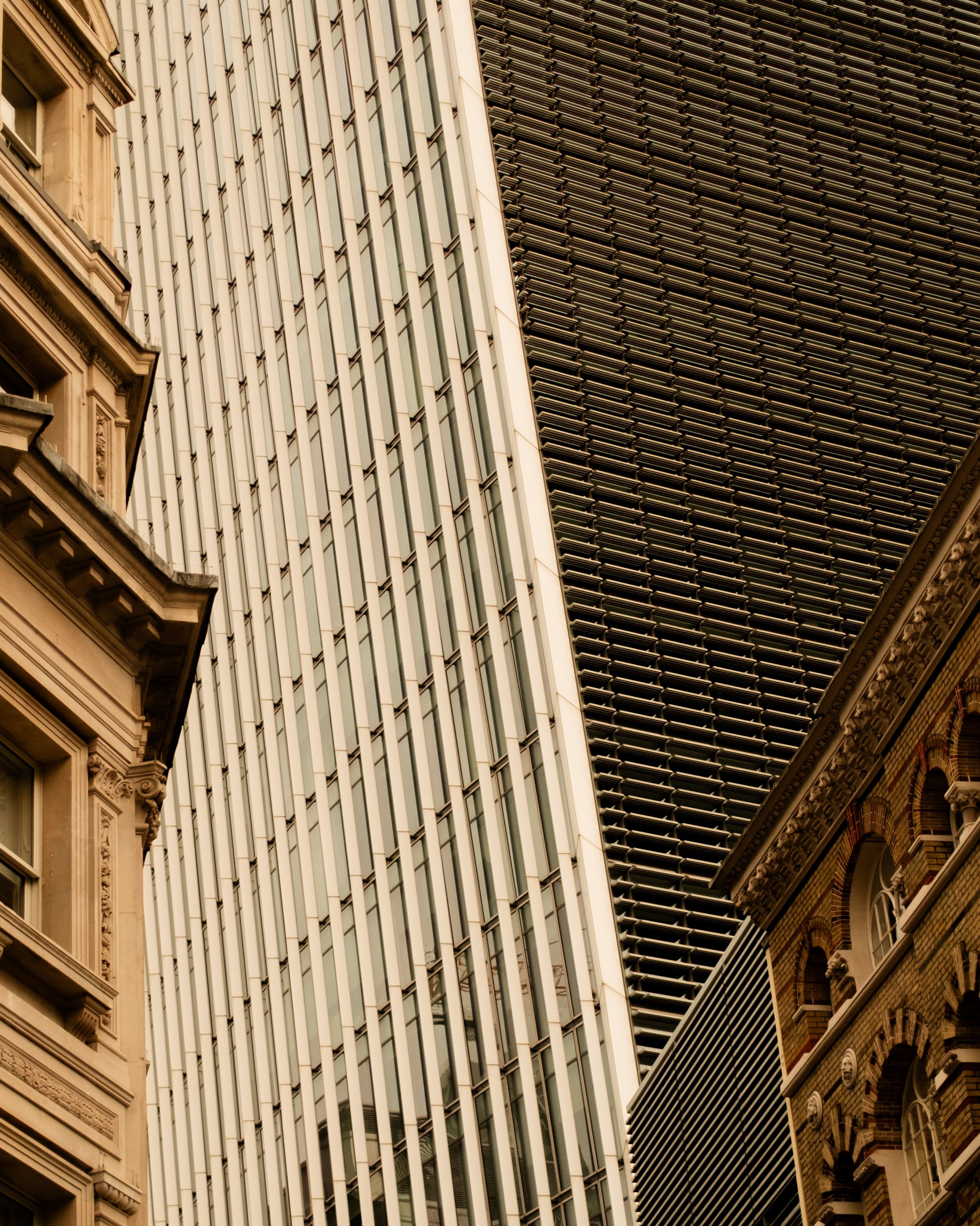Close-up of tall modern glass office buildings next to older architectural buildings in a city. Lionel Chu - Hotel & Travel Photographer