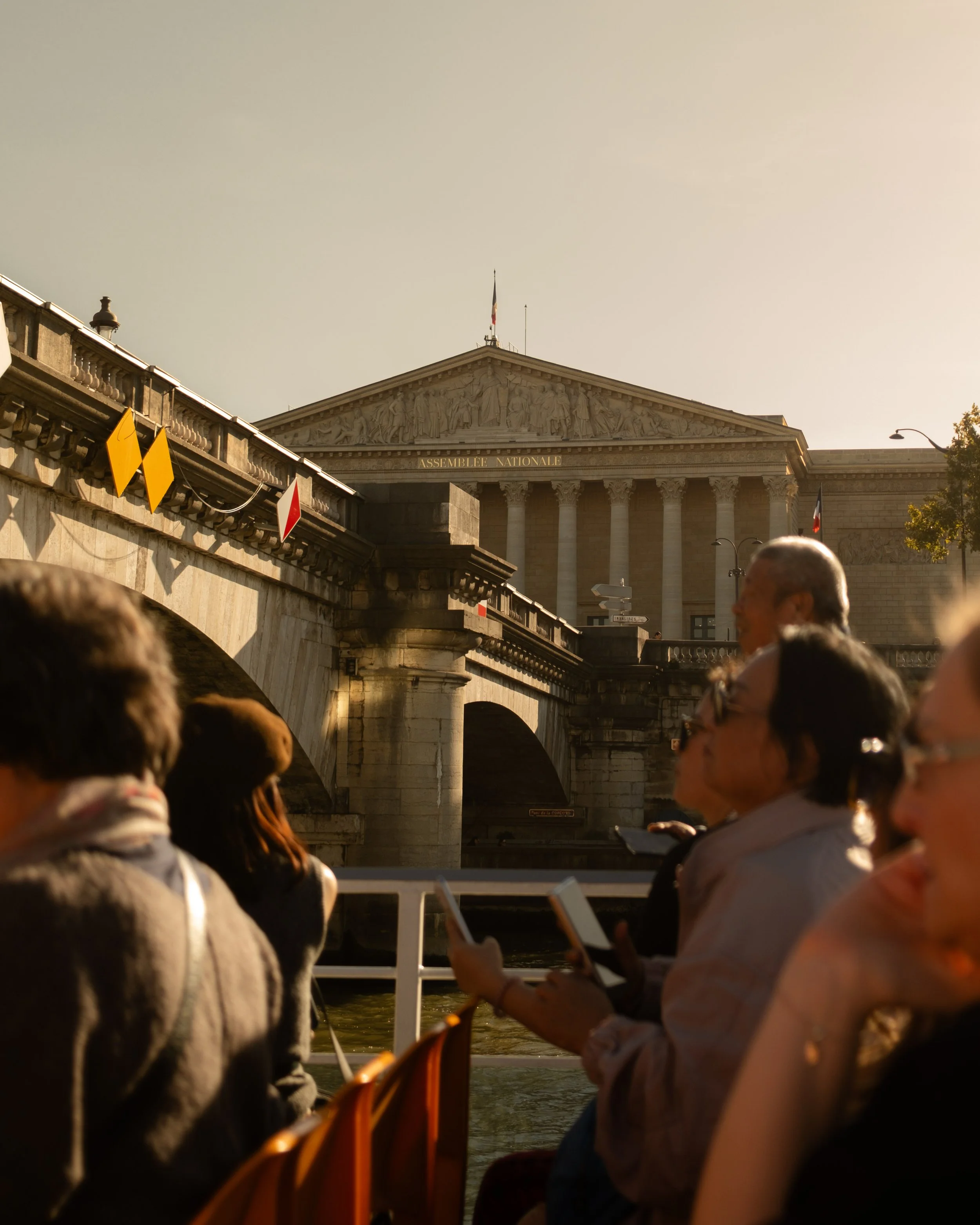 People on a boat tour along the Seine River in Paris with the Palais Bourbon in the background. Lionel Chu - Hotel & Travel Photographer