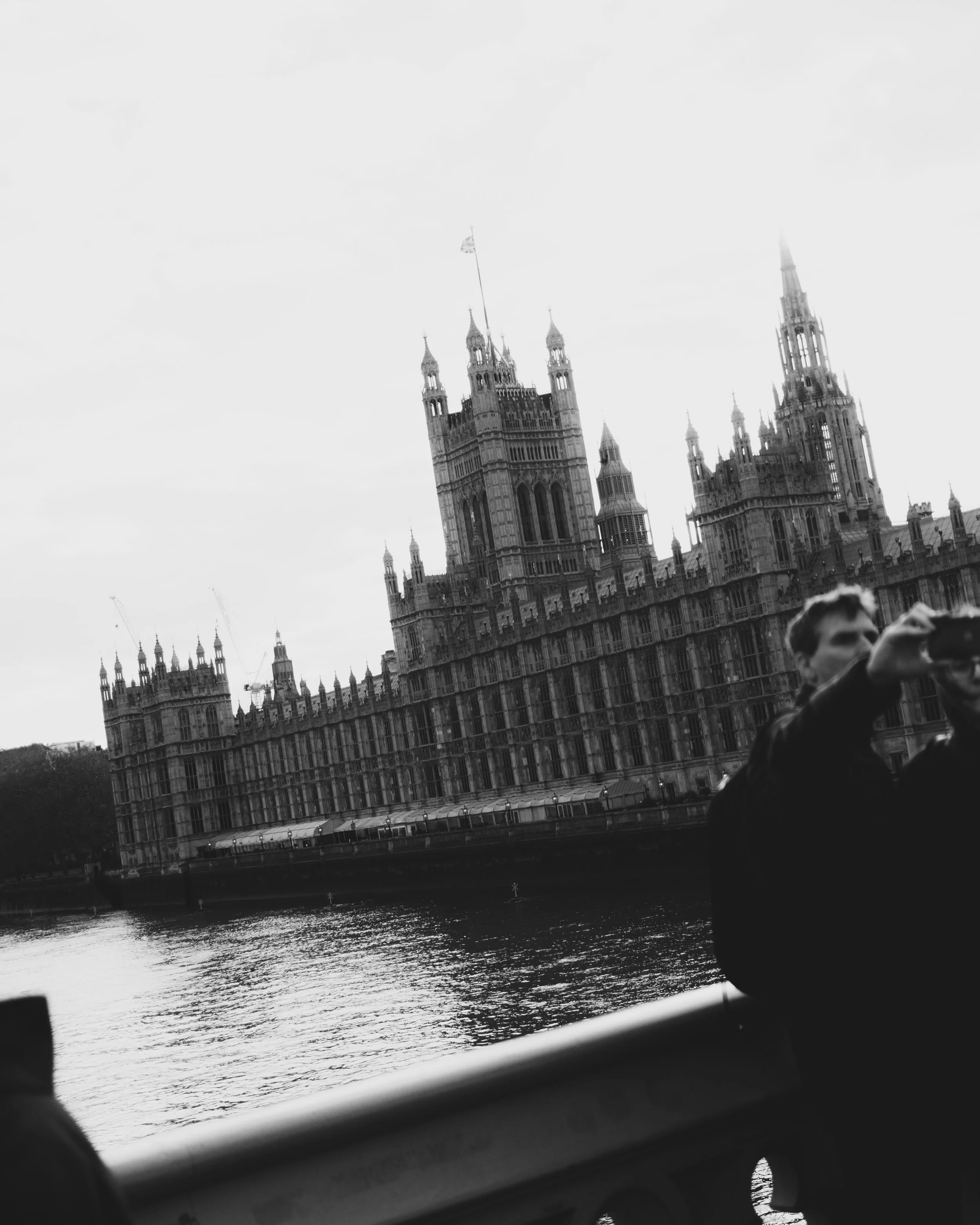 Historical Palace of Westminster in London seen from a bridge over the River Thames, with people taking photos in the foreground, during sunset. Lionel Chu - Hotel & Travel Photographer