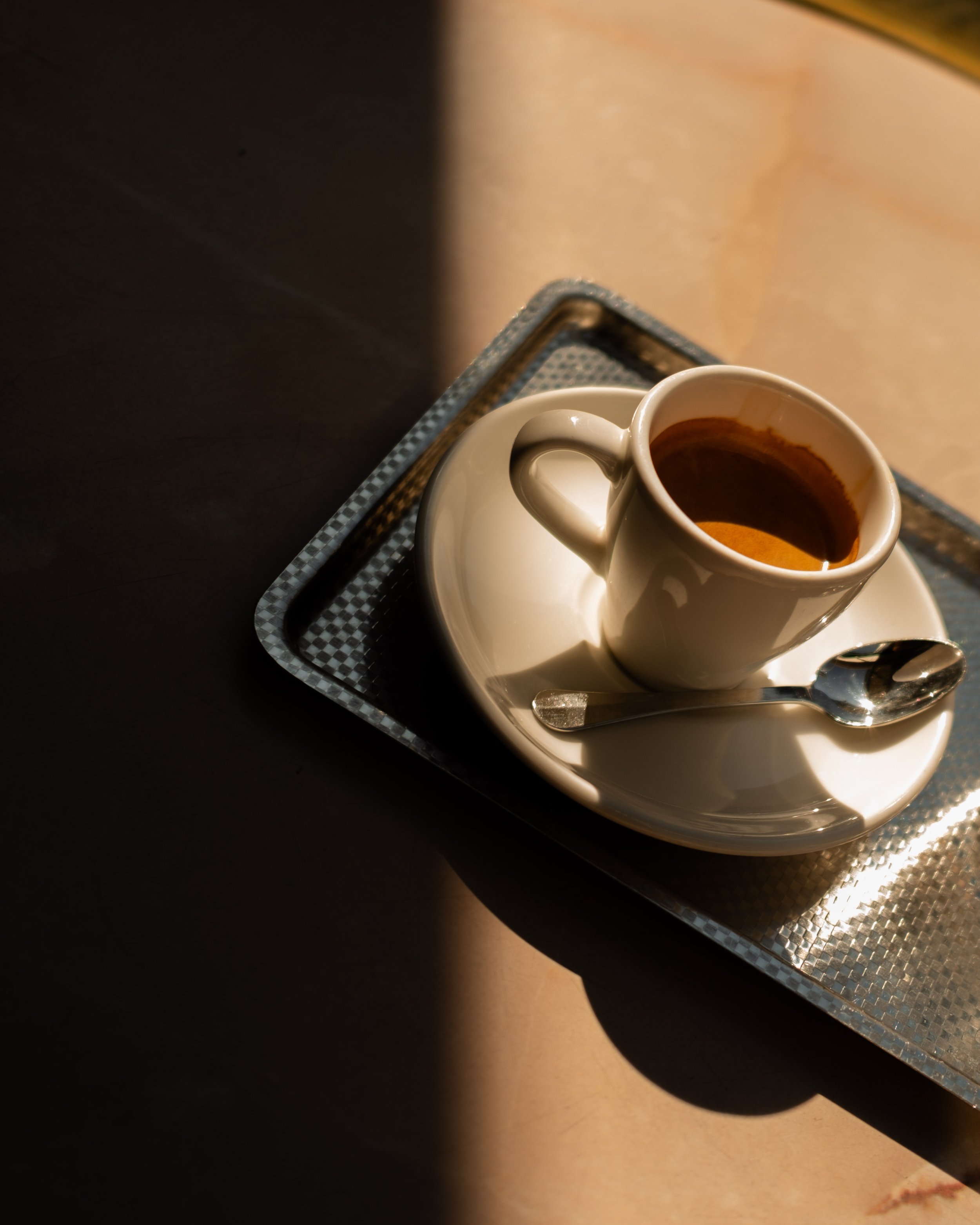 Espresso cup on saucer with spoon on a metal tray. Lionel Chu - Hotel & Travel Photographer.