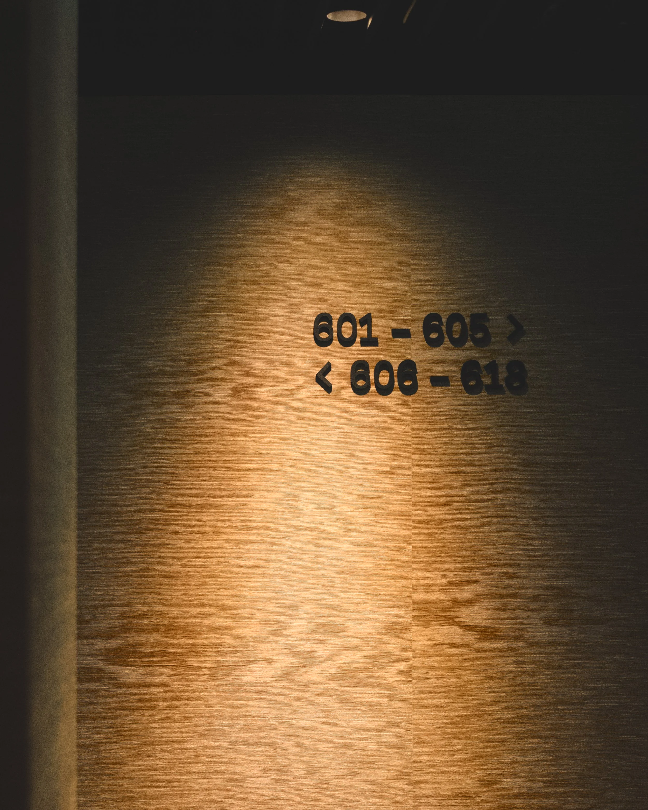 Hotel room directory with room number ranges 601-605 and 606-618 on a textured brown wall.