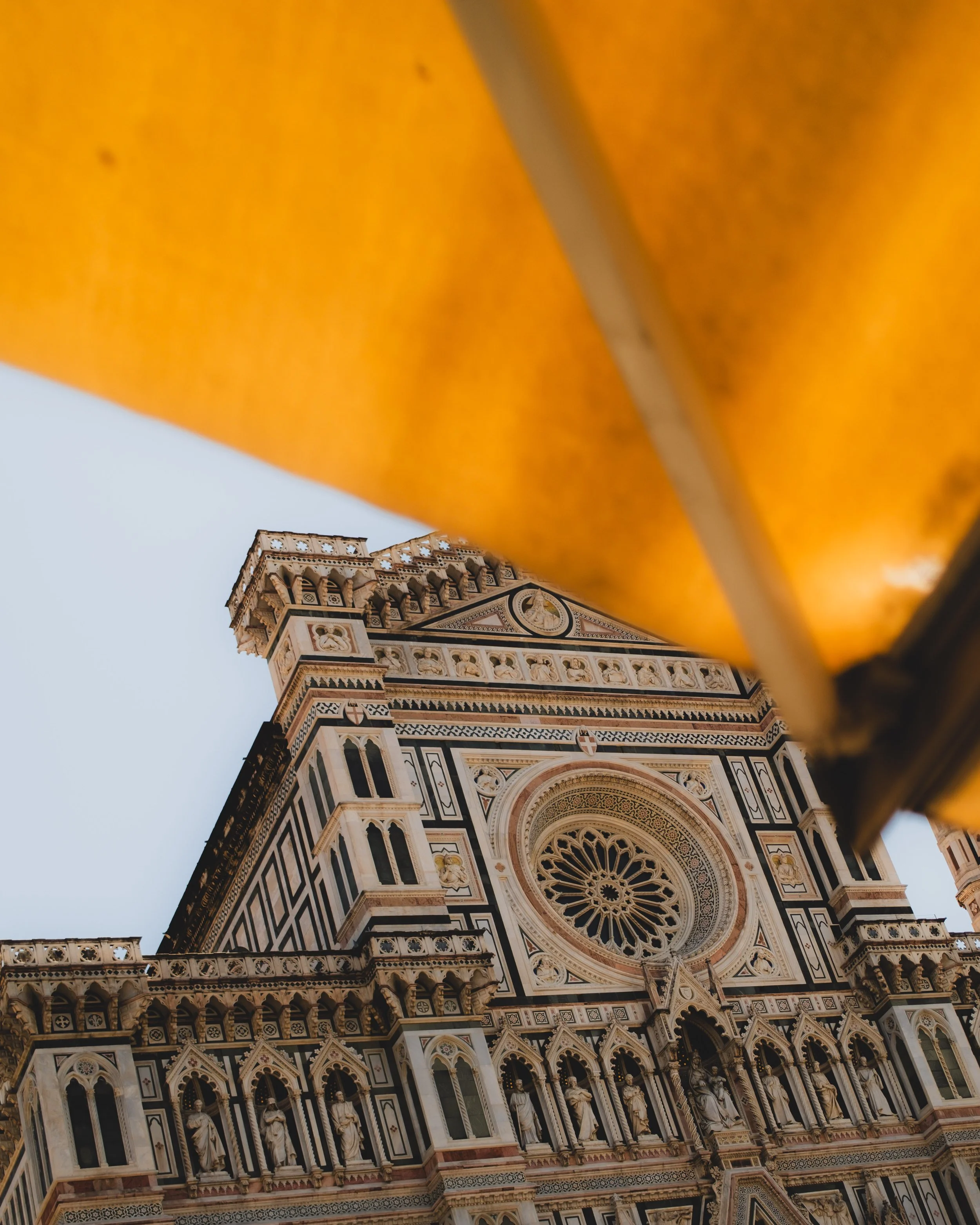 Close-up of the ornate facade of a historic cathedral, seen from below with a section of orange-colored structure in the foreground. Lionel Chu - Hotel & Travel Photographer