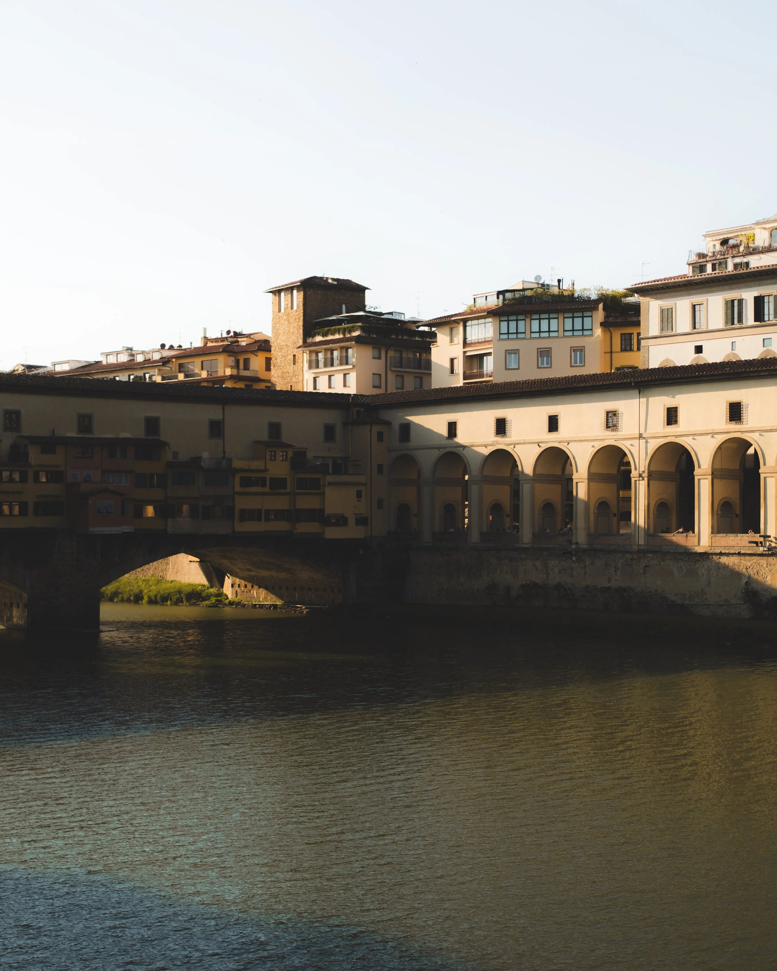 Cityscape with historic bridge and buildings overlooking a river at sunset in Florence, Italy. Lionel Chu - Hotel & Travel Photographer