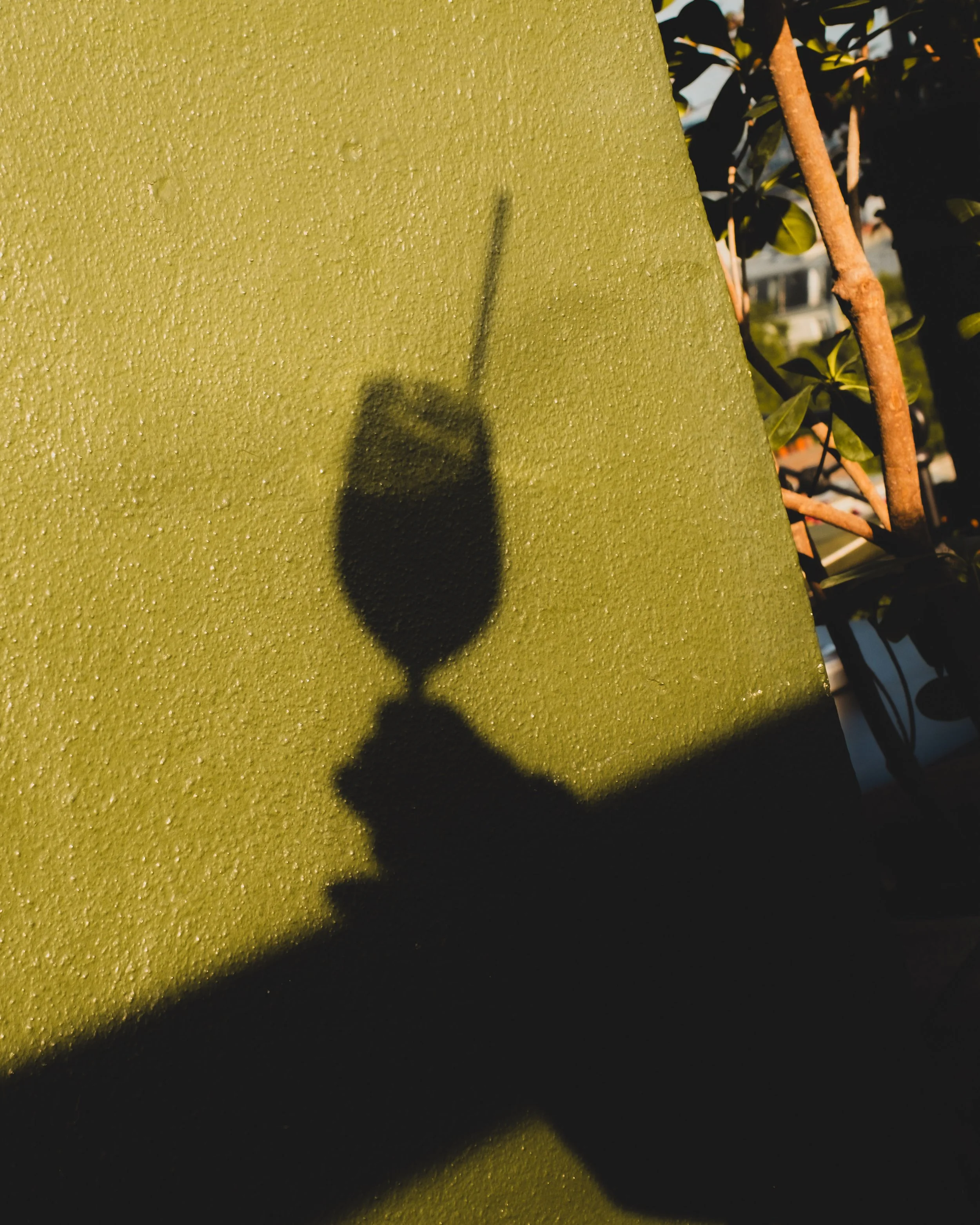 A glimpse of the shadow of a hand holding a cocktail on a glass wall, from the rooftop of a luxury hotel