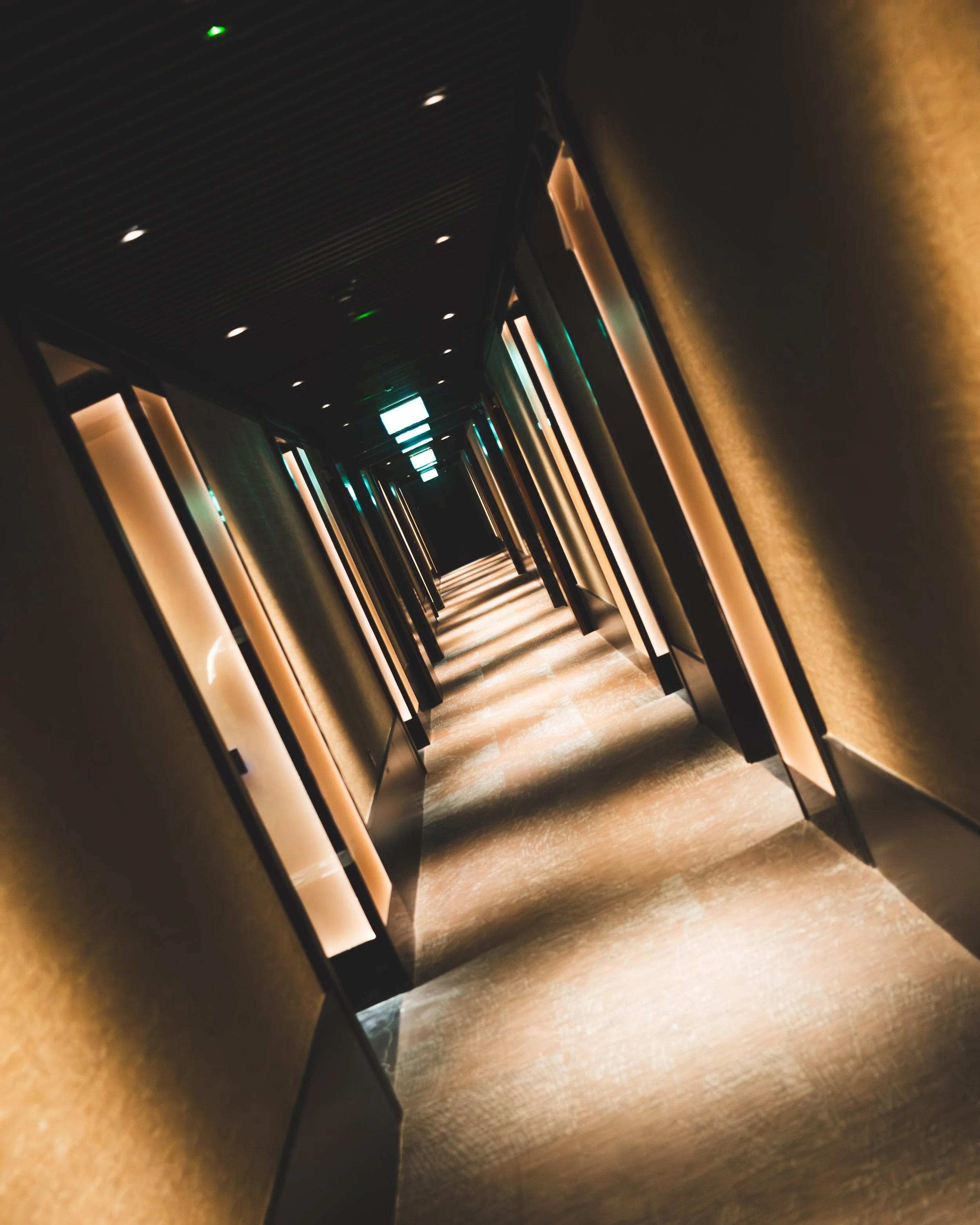 A dark corridor with illuminated panels along its walls and ceiling, creating a sleek, modern look.