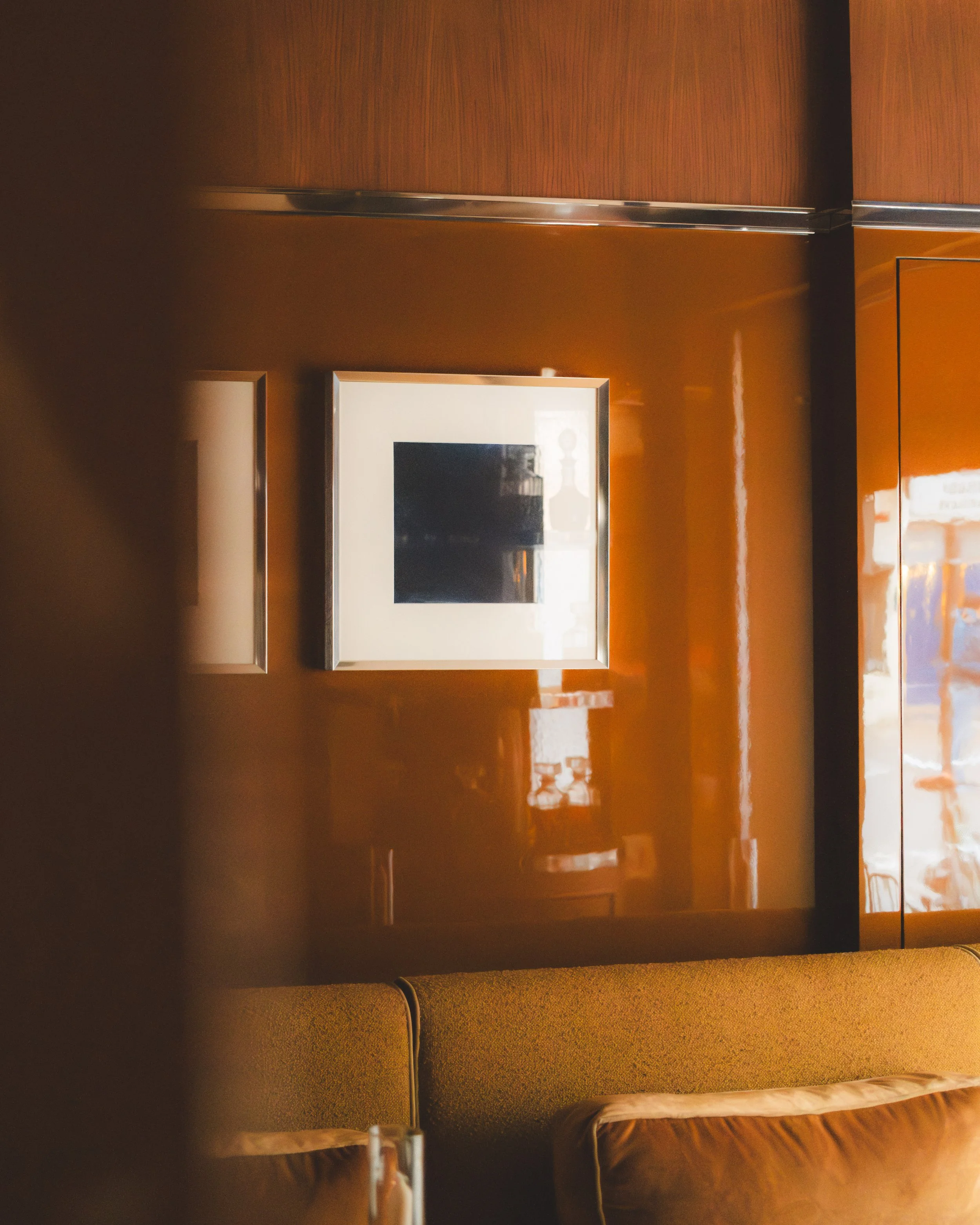 Interior of an elevator with wooden paneling, a framed mirror on the wall, and brown upholstered seats.