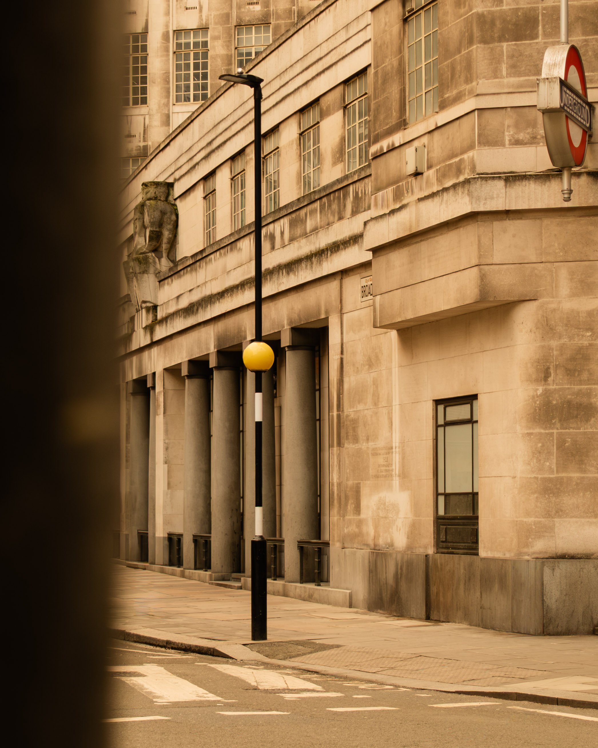 An urban street corner with a stone building, a streetlamp, and a London Underground sign. Lionel Chu - Hotel & Travel Photographer