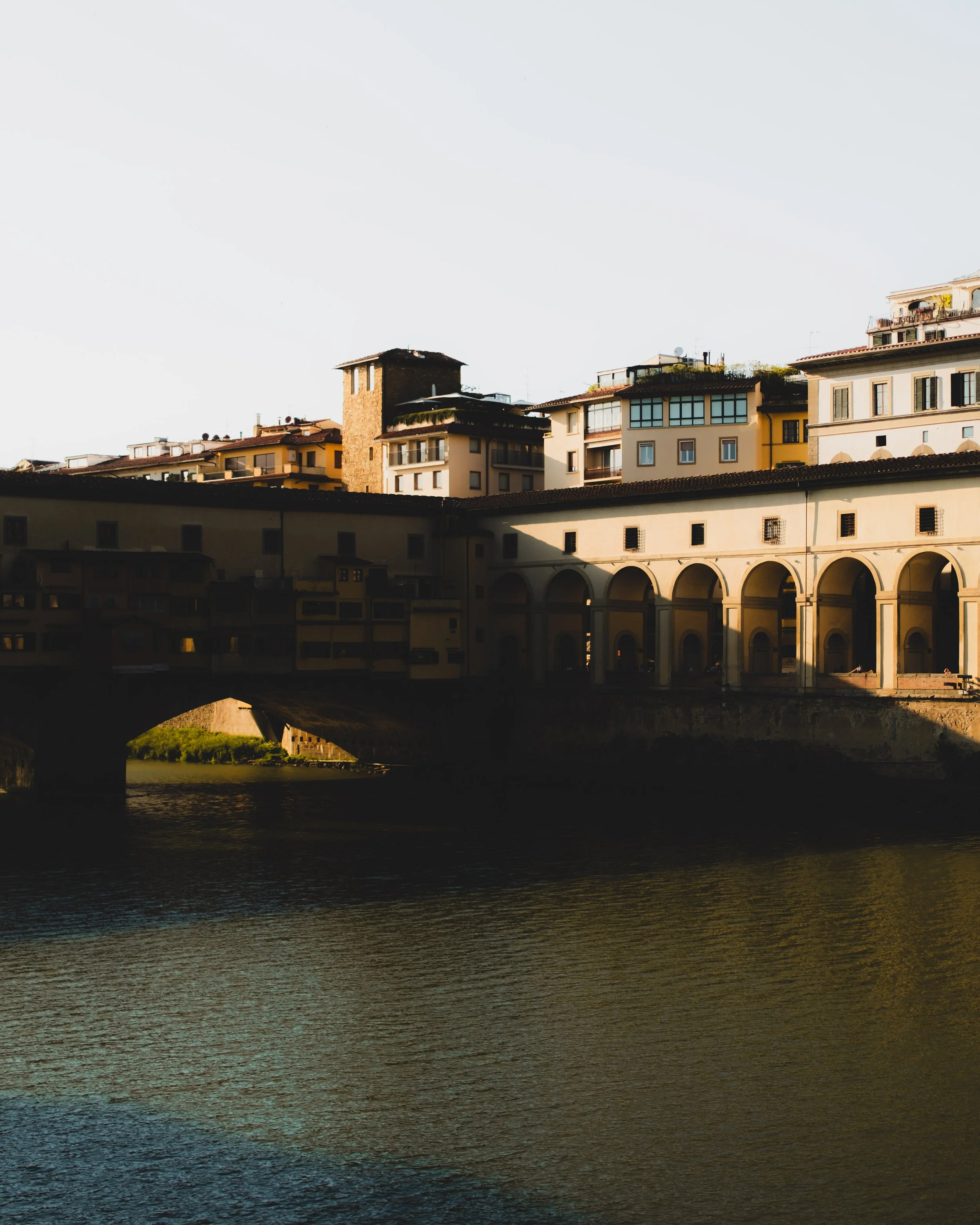 Cityscape with historic bridge and buildings overlooking a river at sunset in Florence, Italy. Lionel Chu - Hotel & Travel Photographer