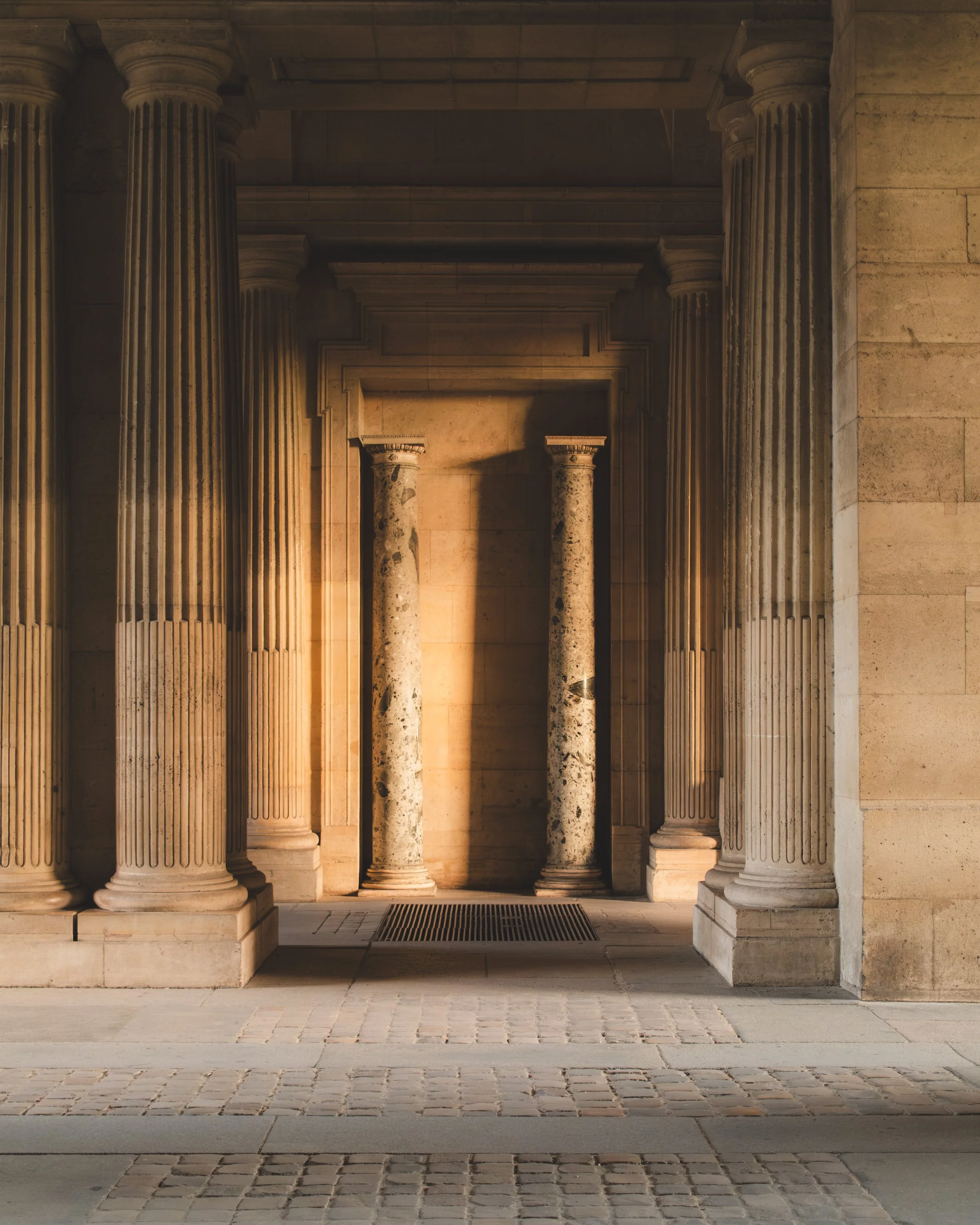 Ancient Greek or Roman-style stone columns and architecture, with warm lighting highlighting the classical design.