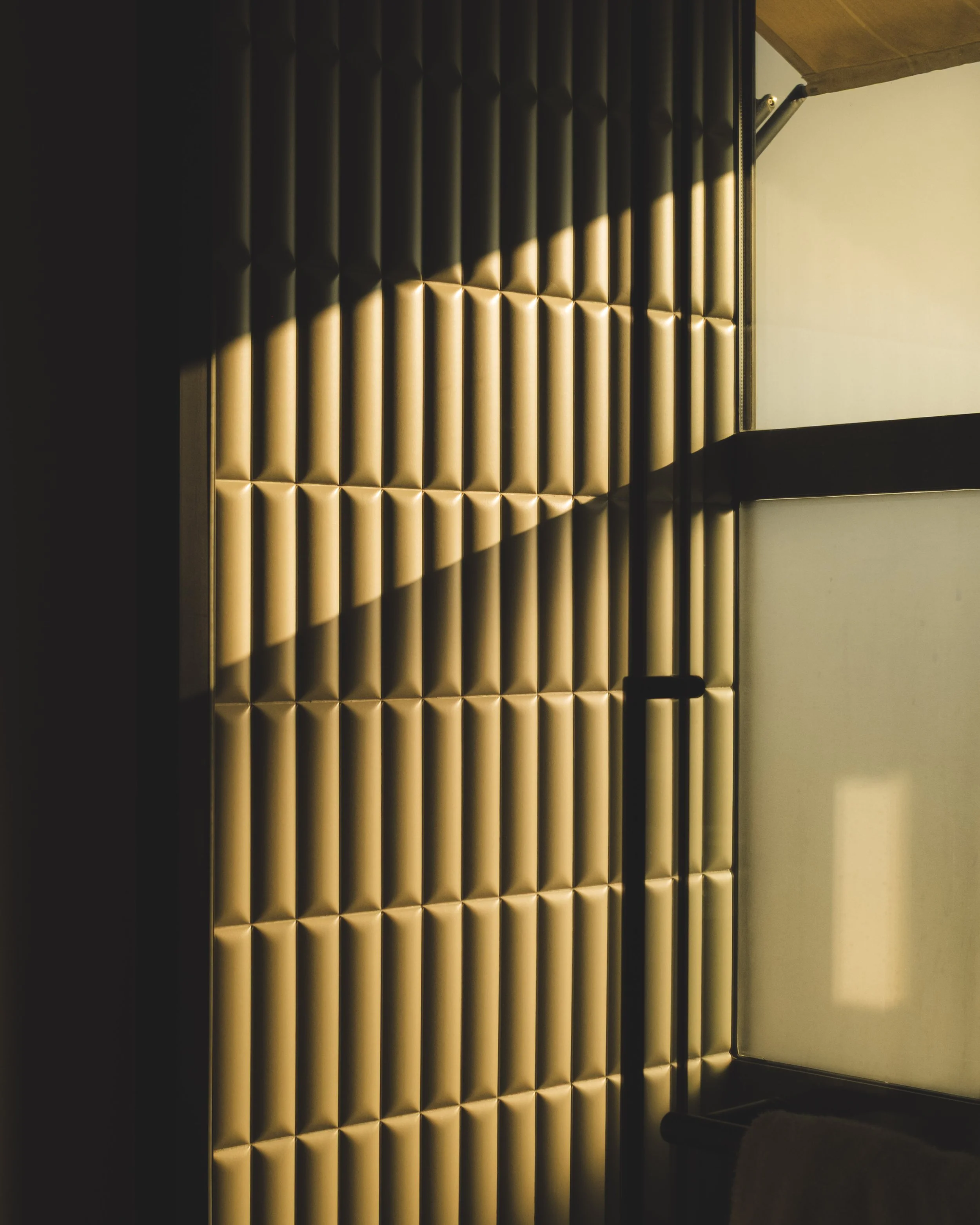 Interior of a luxury hotel bathroom, illuminated by a ray of sunlight, composed of vertical light green bricks.