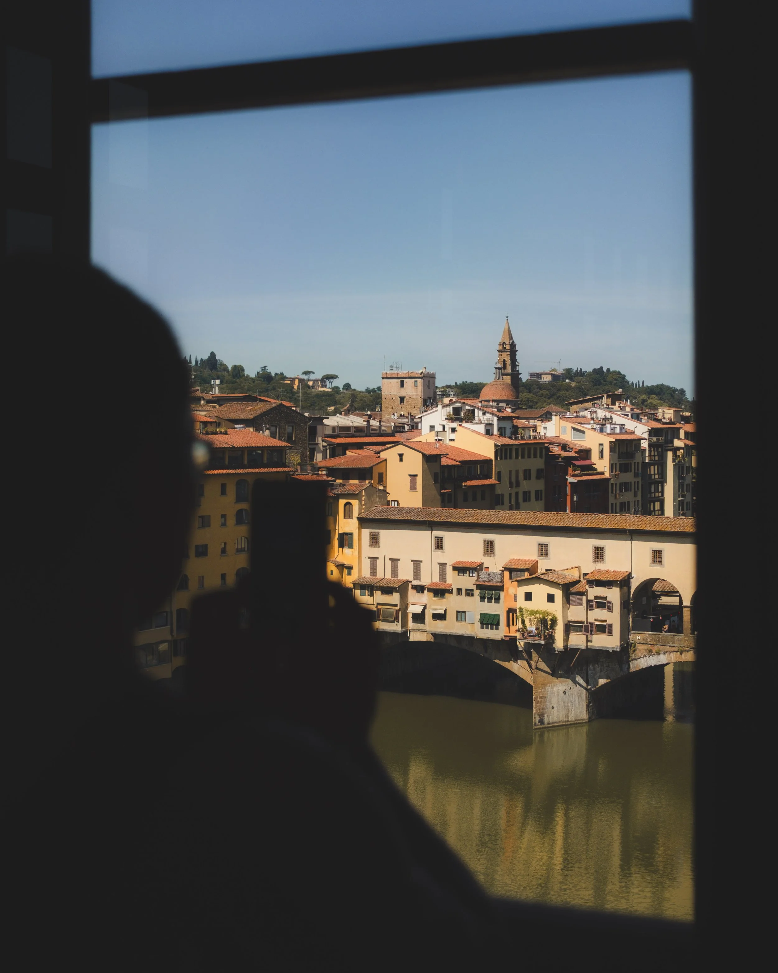 View of the Ponte Vecchio from the Uffizi Gallery in Florence, silhouette of a person taking a photo with their smartphone