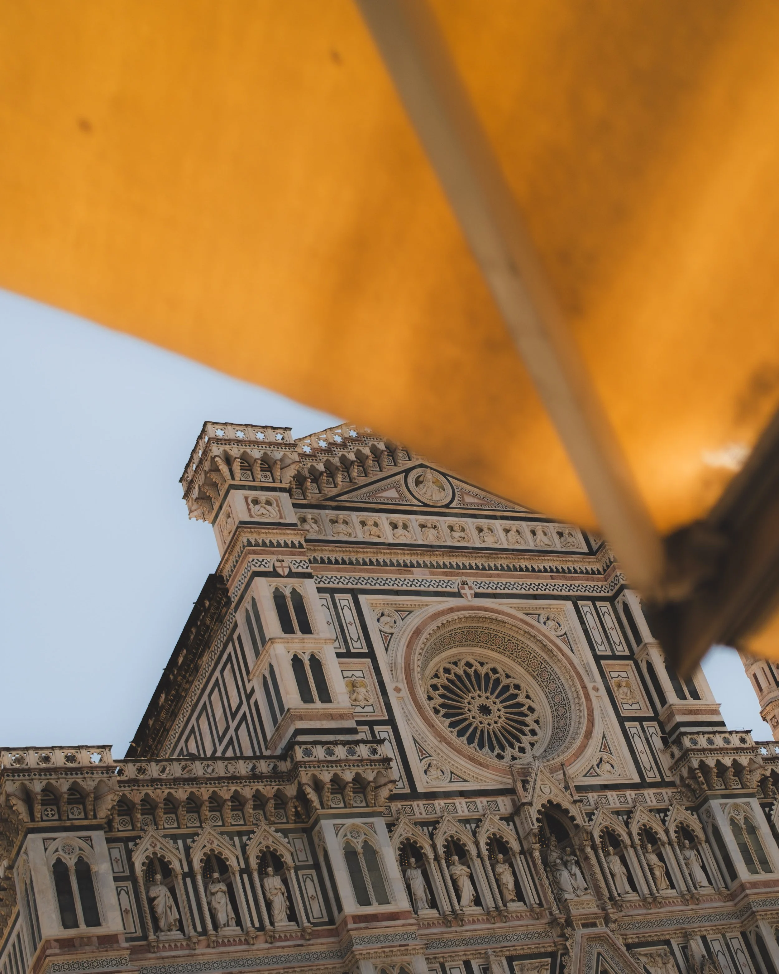 Close-up of the ornate facade of a historic cathedral, seen from below with a section of orange-colored structure in the foreground. Lionel Chu - Hotel & Travel Photographer