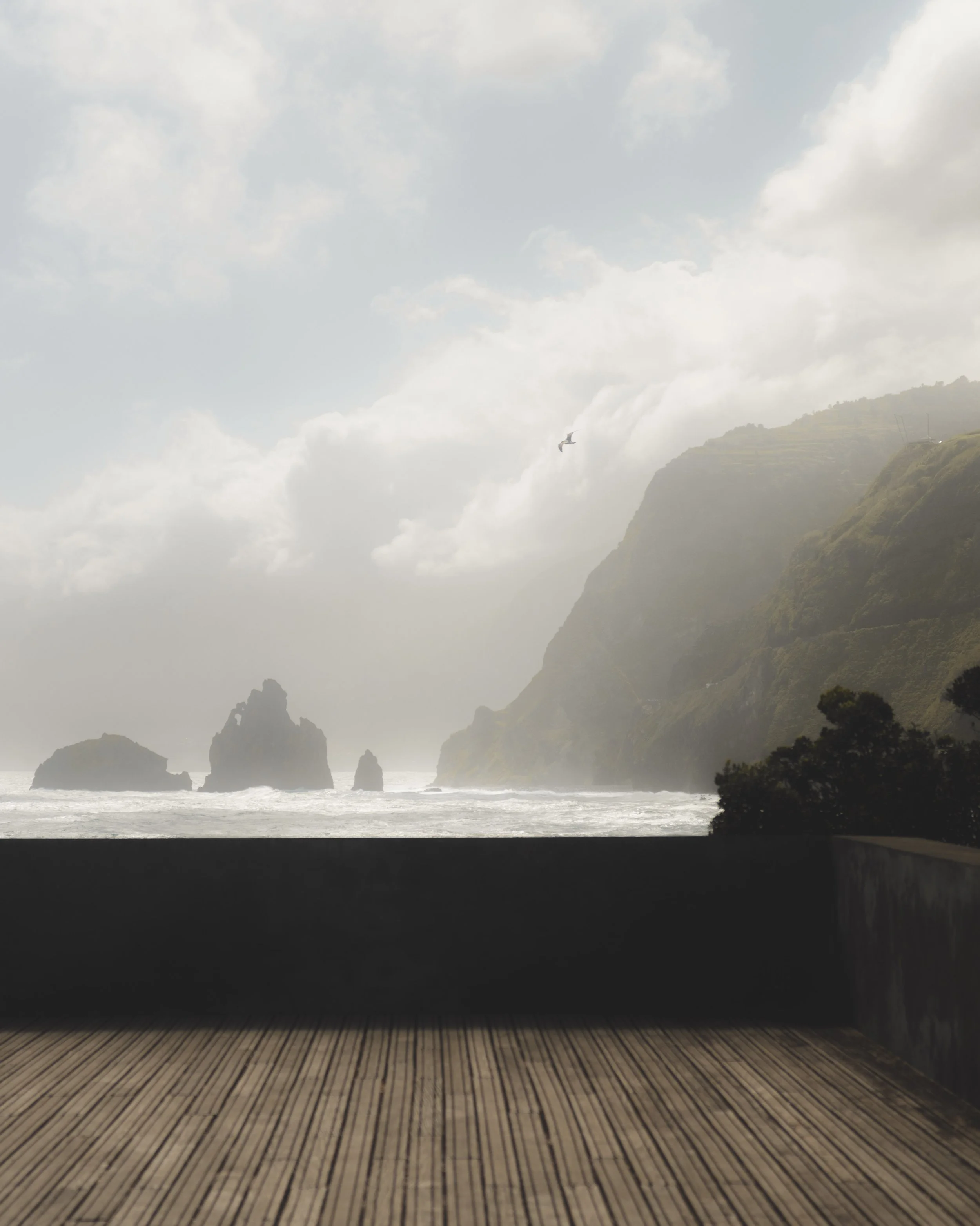 View from a theater stage showing a scenic backdrop of the ocean with rocks and cliffs, clouds in the sky, and seagulls flying, framed by a wooden stage floor.
