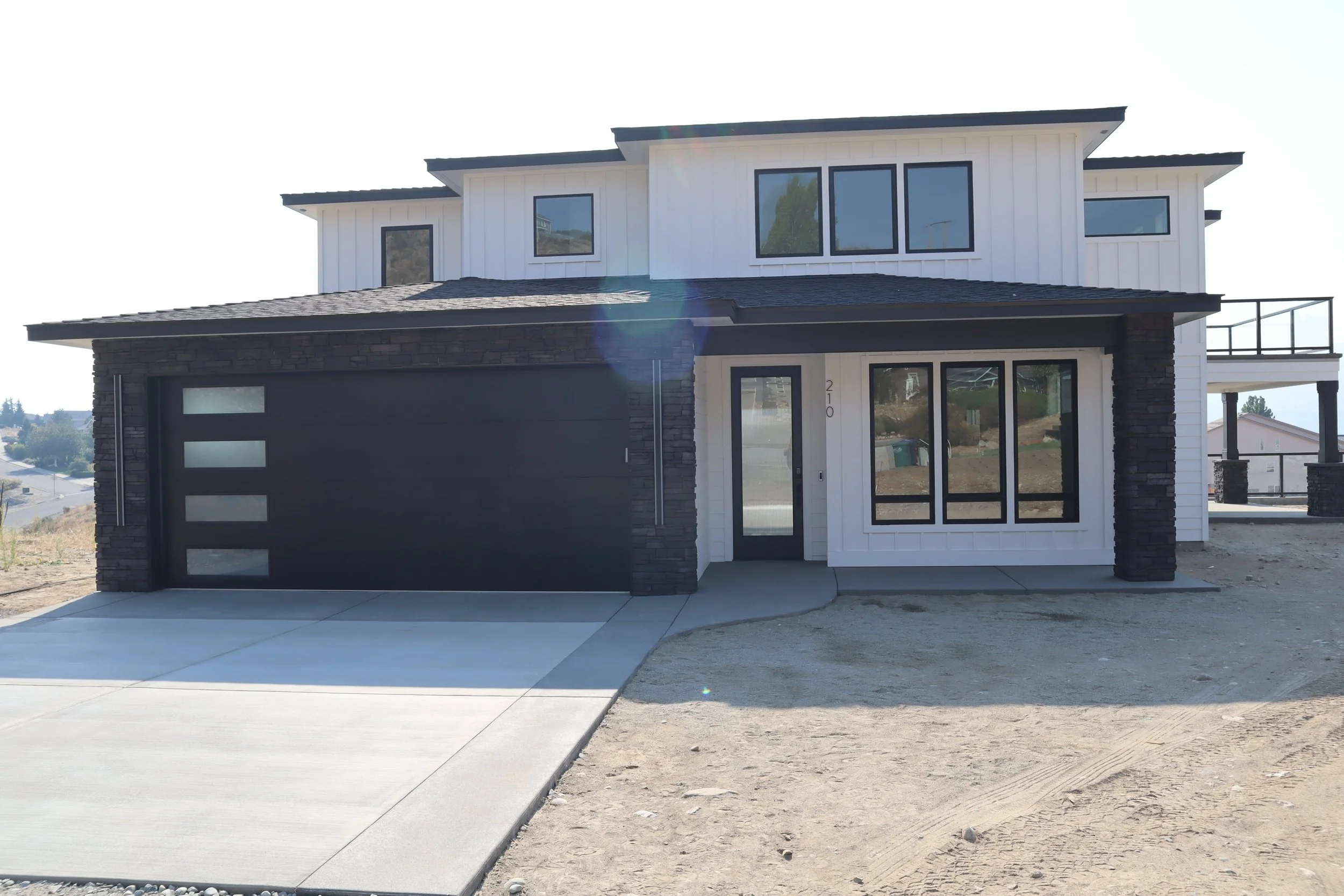 Modern two-story house with black garage door and white siding
