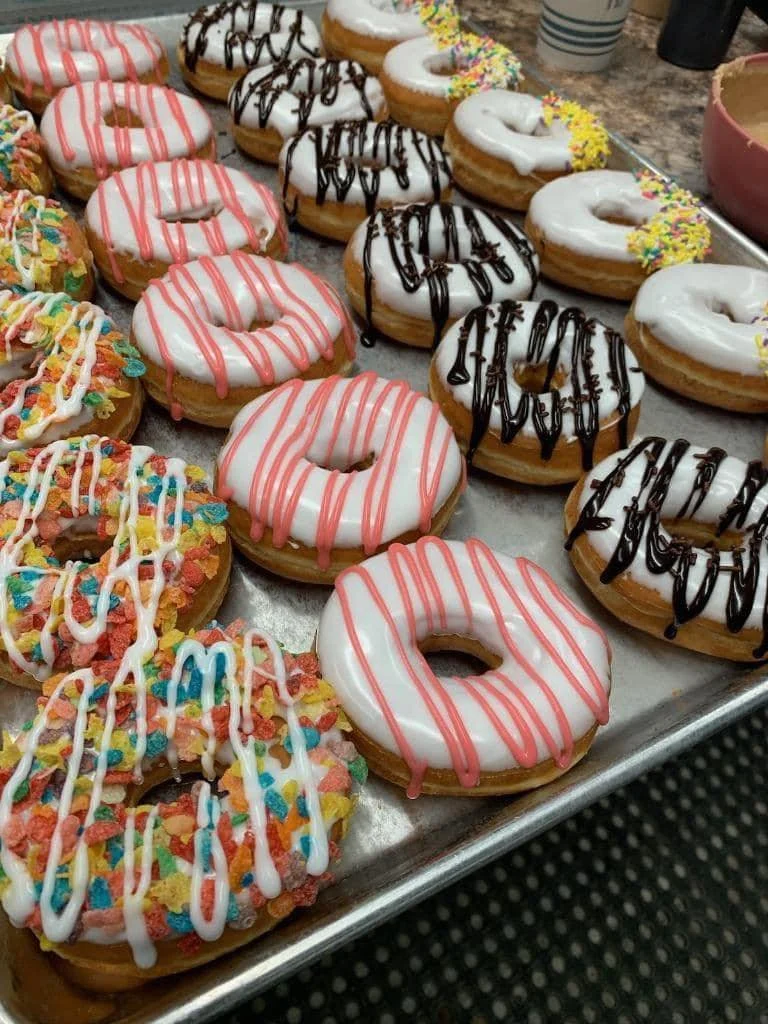 Assorted decorated donuts with various toppings and icing on a baking sheet.