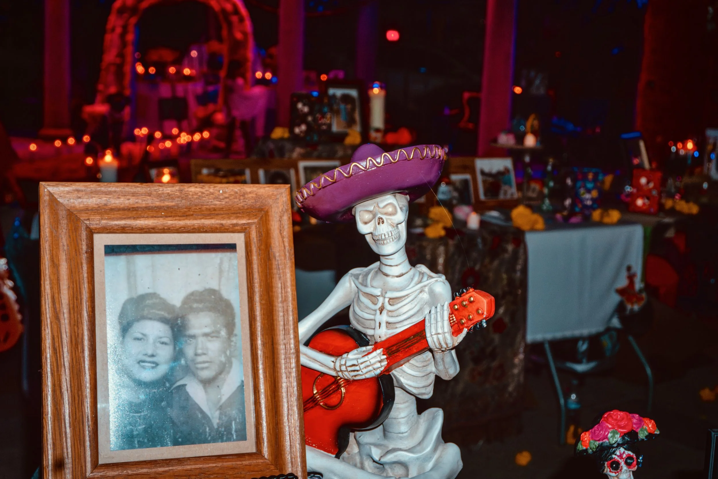 Picture of a couple next to a skelton as part of decorations for a Day of the Dead altar.