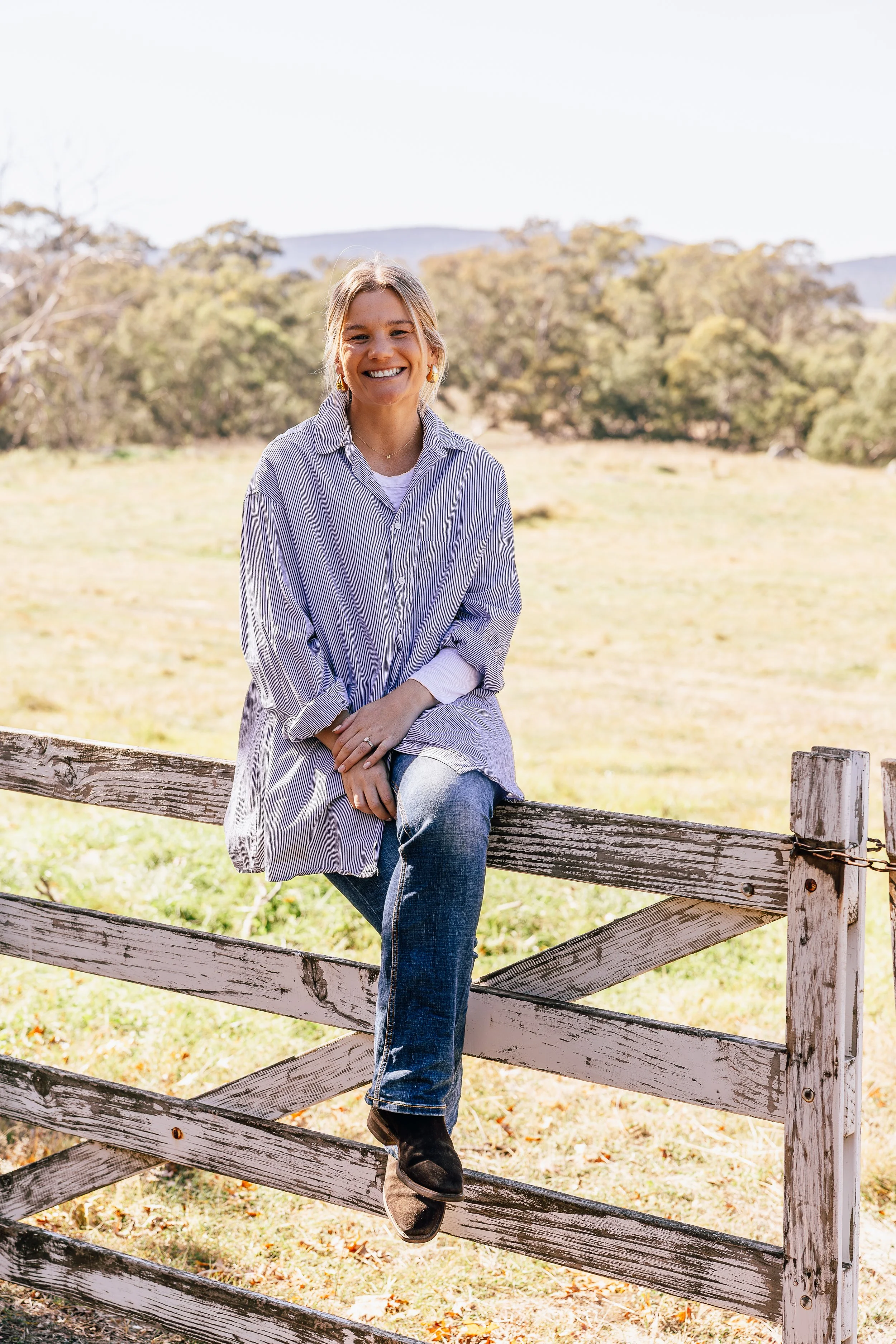 Millie Hardie smiling while sitting on a farm fence in rural NSW, representing the grounded and practical outcomes of the Pep Talk Mini Course by The Pocket Psychologist