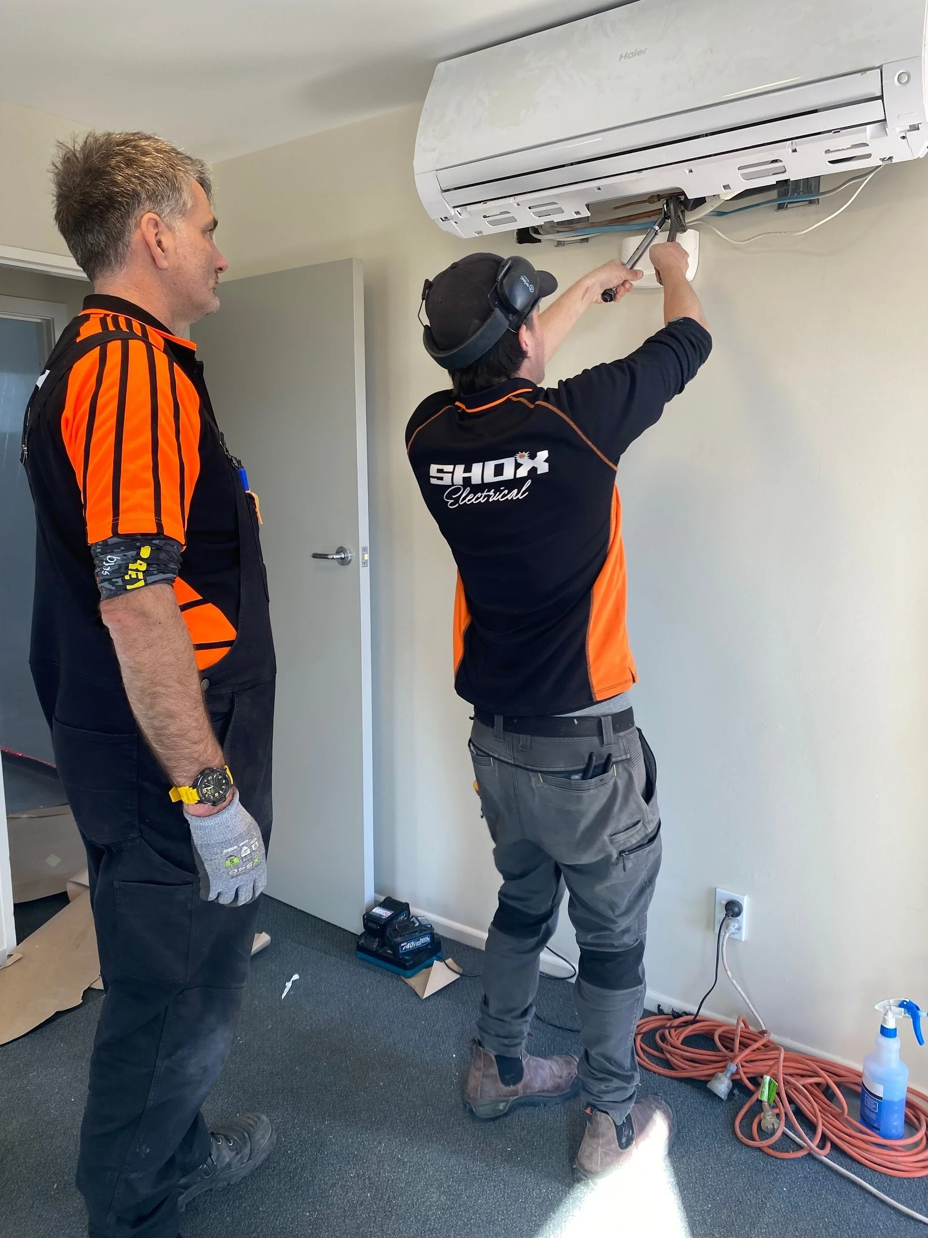 Shox Electrical technicians installing a high-wall heat pump in Christchurch