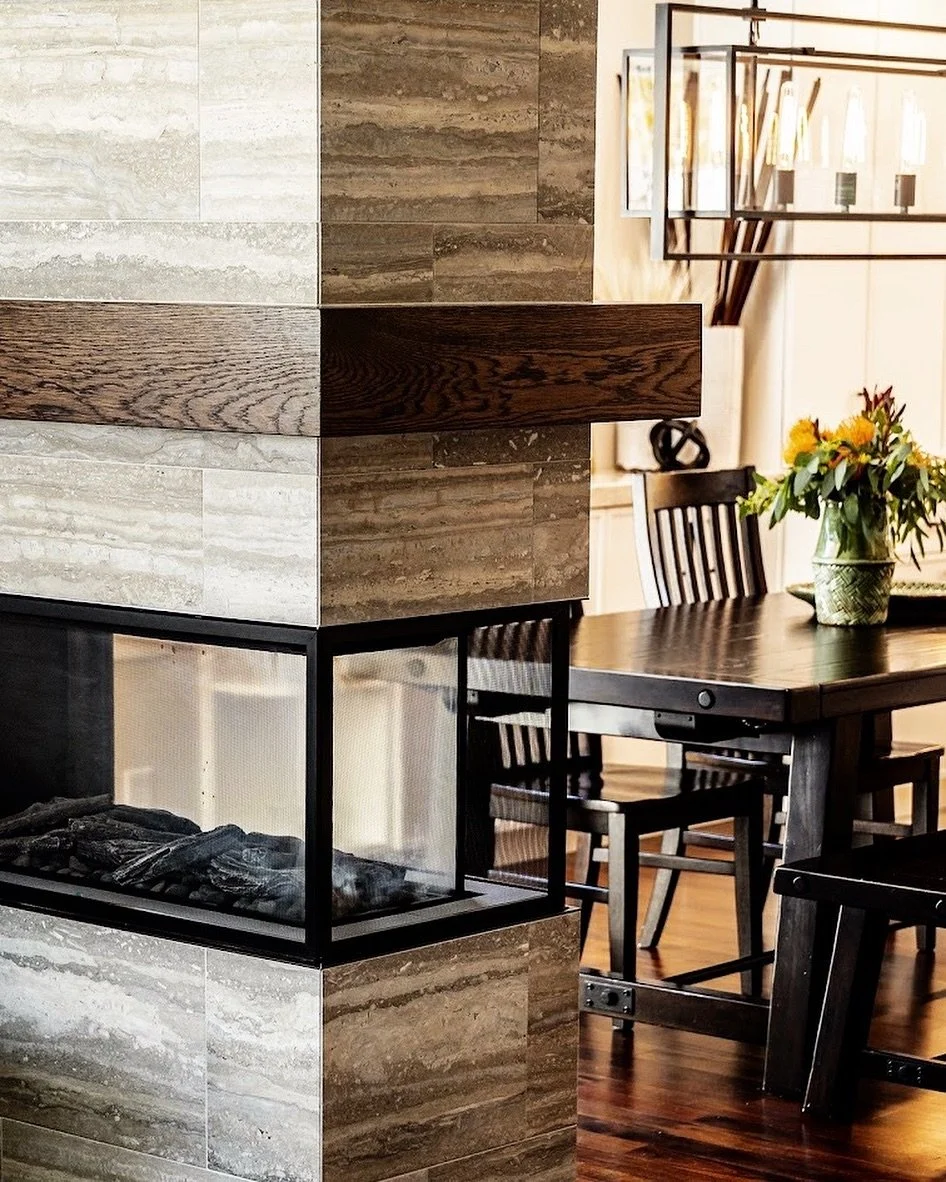 We designed this custom fireplace to give division between our clients living room and dining room area. Clad in earthy toned Ocean Blue Travertine and Walnut Slab. Contractor: @dfsconstructs #interiordesign #utahstyleanddesign #saltlakecity #utah #f
