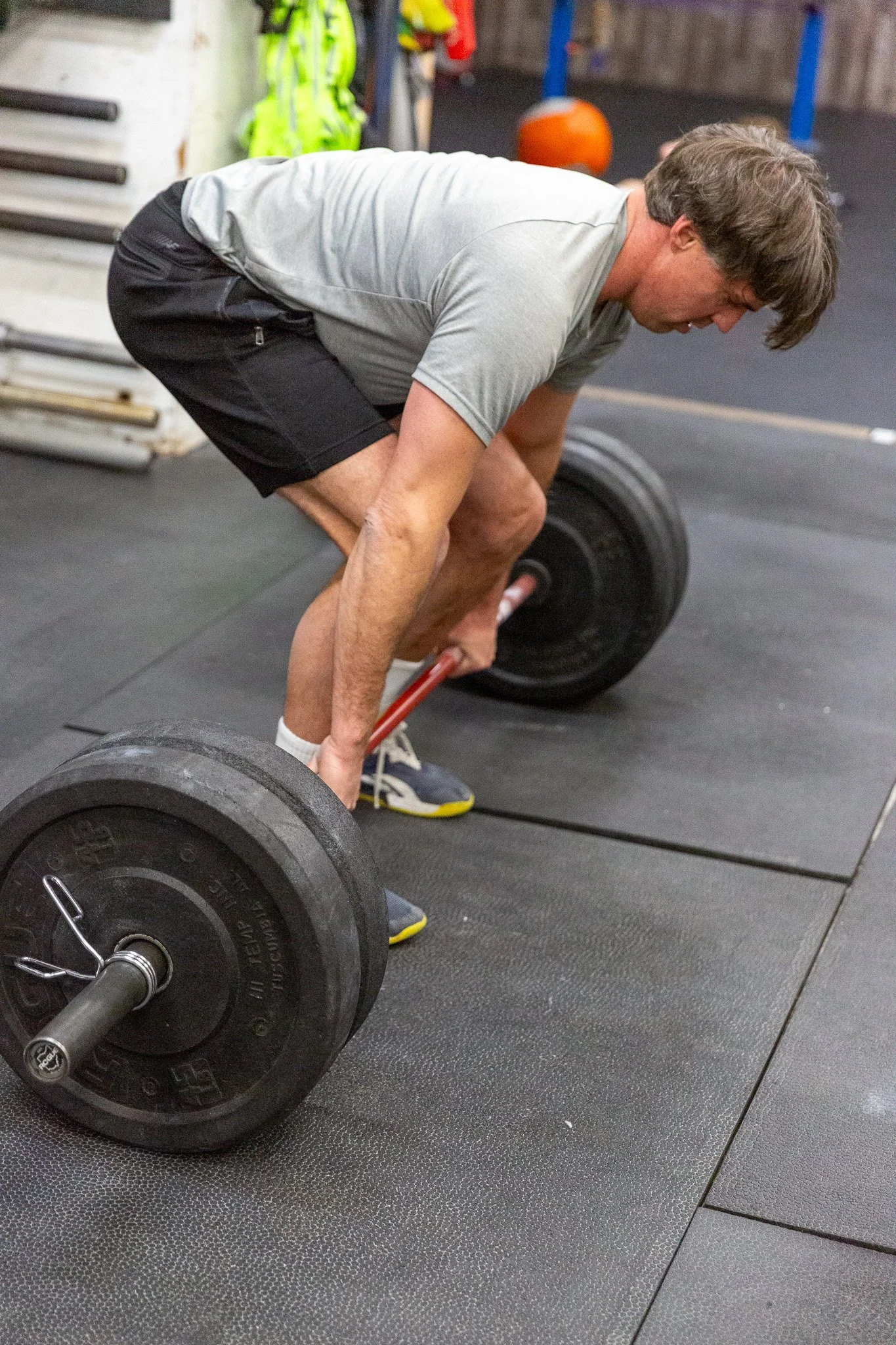 A man performing a deadlift exercise in a gym with large weights.