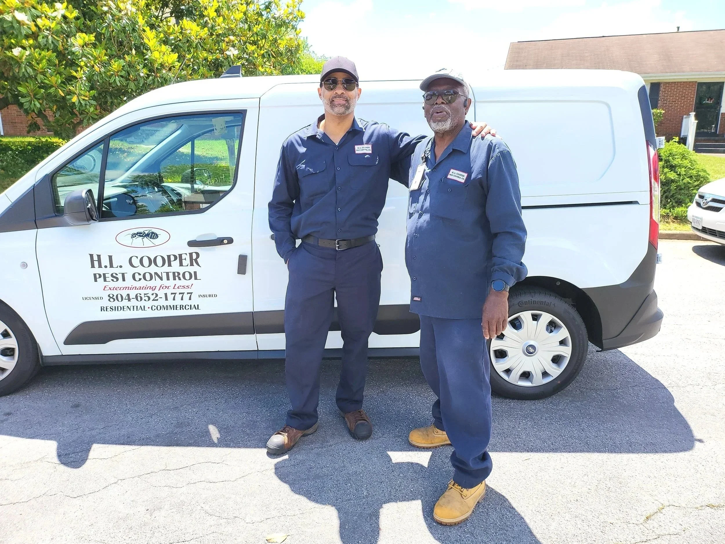 Two men in blue uniforms standing by  white truck