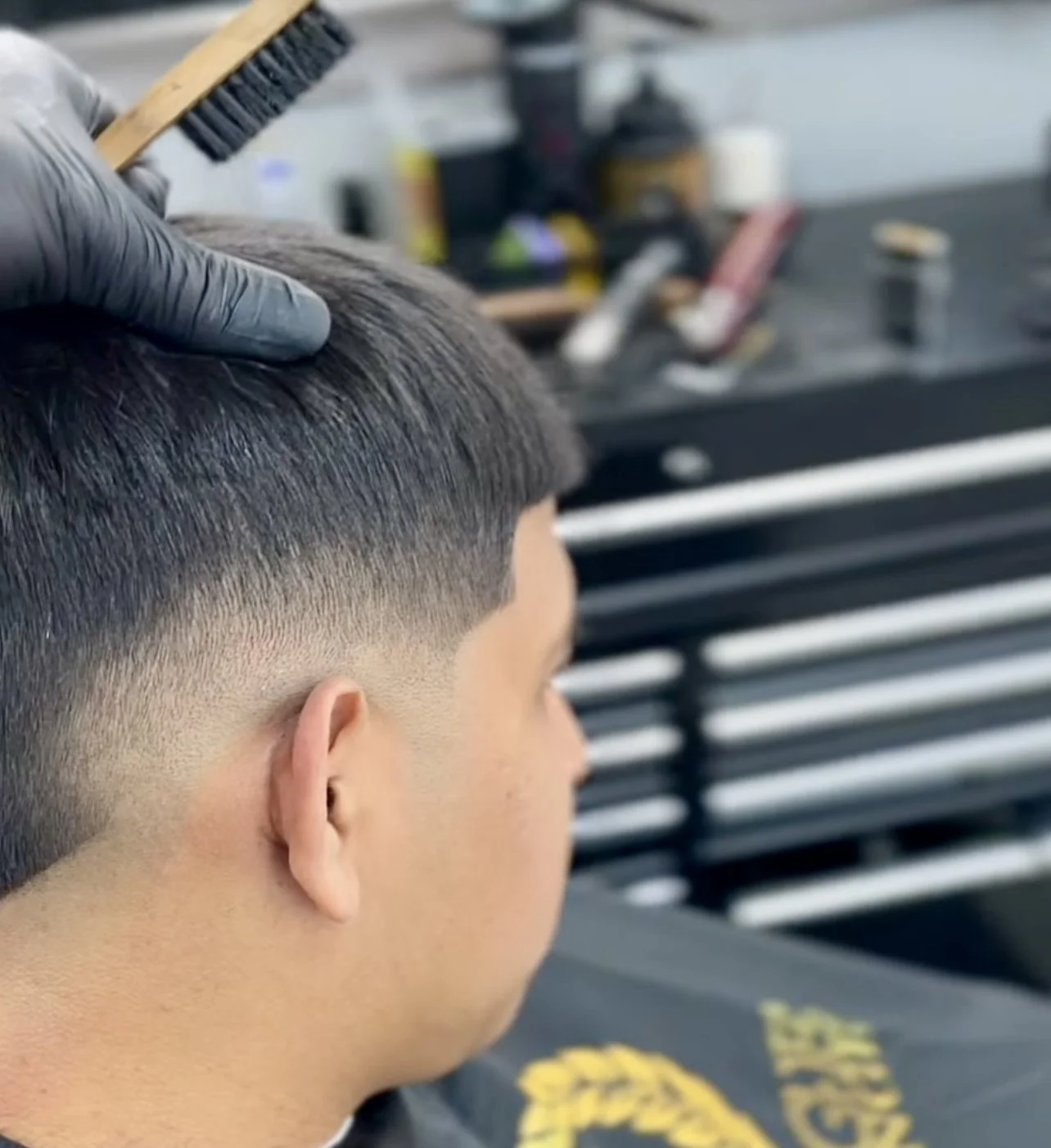 Man getting a fade haircut at a barbershop with barber holding a brush.