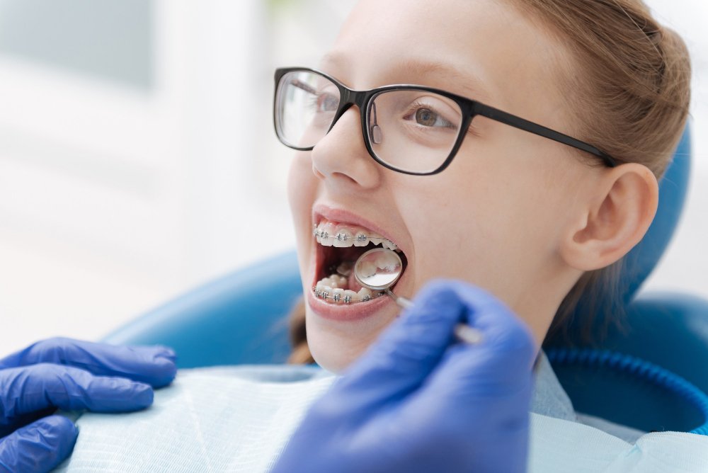 Girl is having dental checkup and wearing the metal braces.