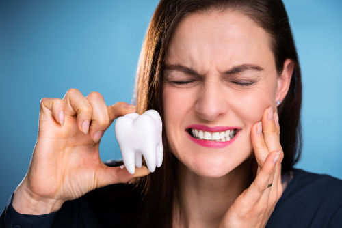 Woman holding a a teeth, promoting dental pain.