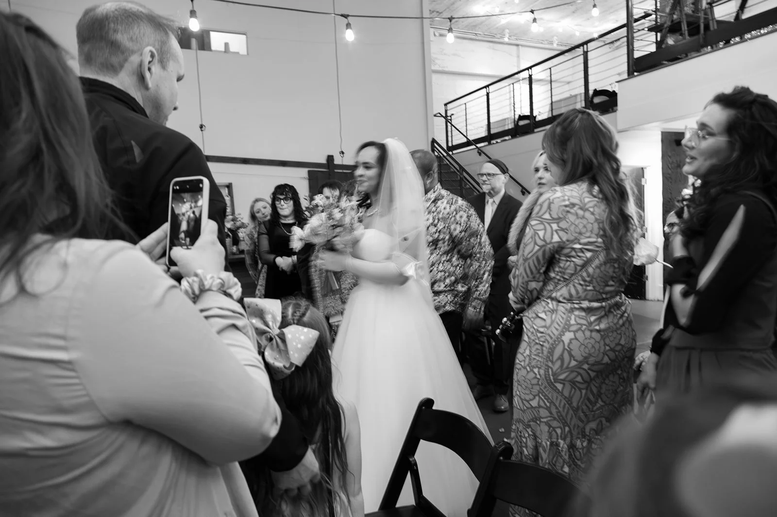 Bride walking through guests during the wedding ceremony, surrounded by loved ones in a candid, documentary moment.