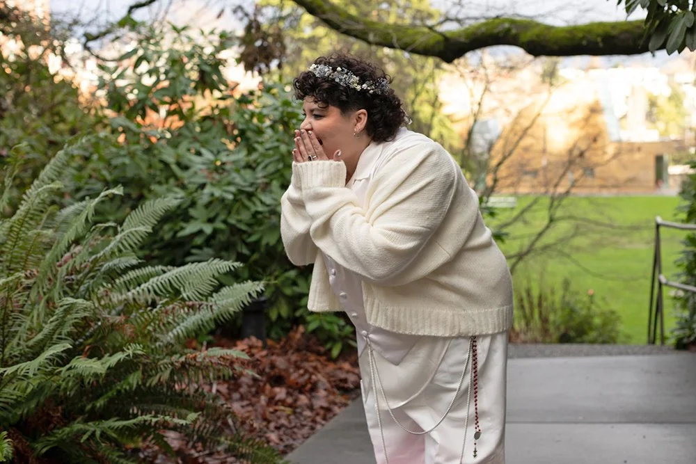 Emotional candid moment as the groom reacts with surprise and joy during a first look in a garden setting.