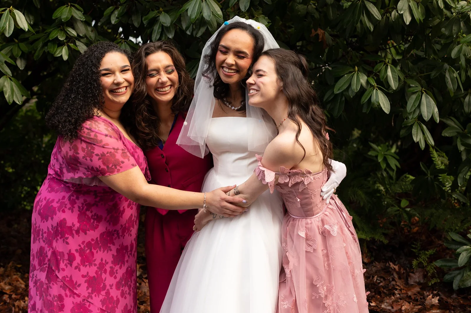 Bride laughing with friends during an outdoor wedding portrait, joyful candid moment in a Seattle garden setting.